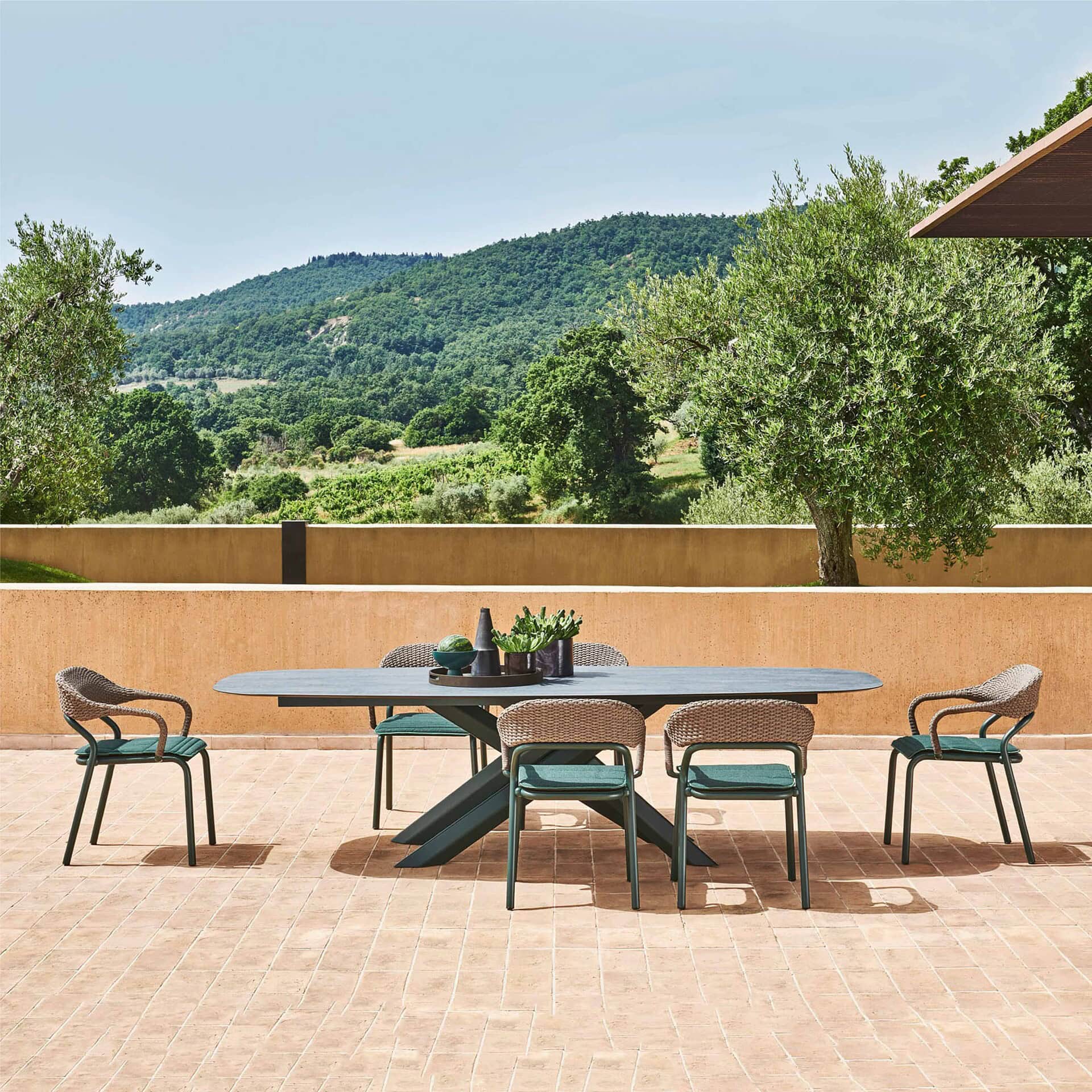 Stylish outdoor dining table with six chairs on a patio with scenic mountain view.