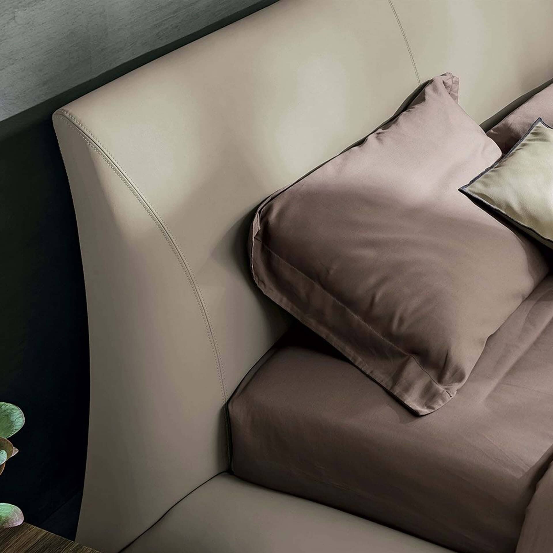 Luxurious beige upholstered bed with elegant stitching and plush pillows for upscale bedroom decor.