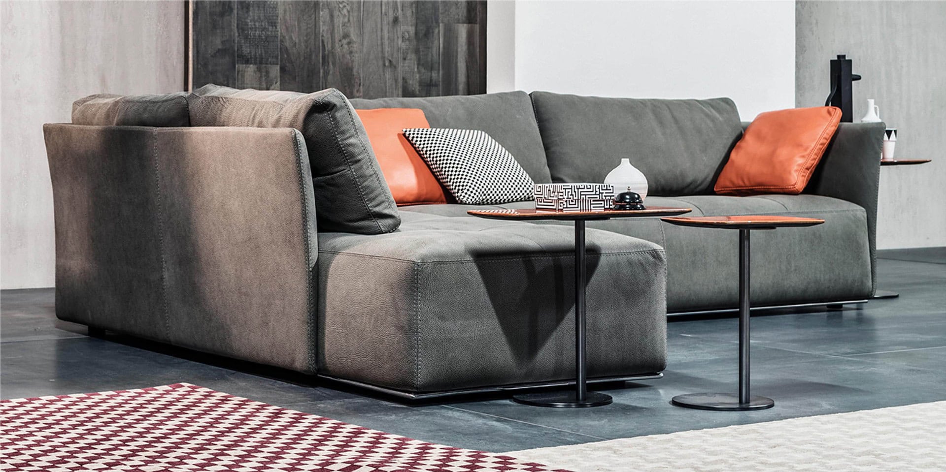 Modern gray sectional sofa with stylish accent pillows and sleek black side tables in a contemporary living room.