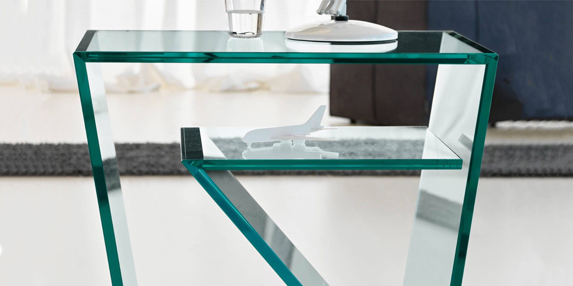 Sleek glass side table with airplane decor for modern living rooms.