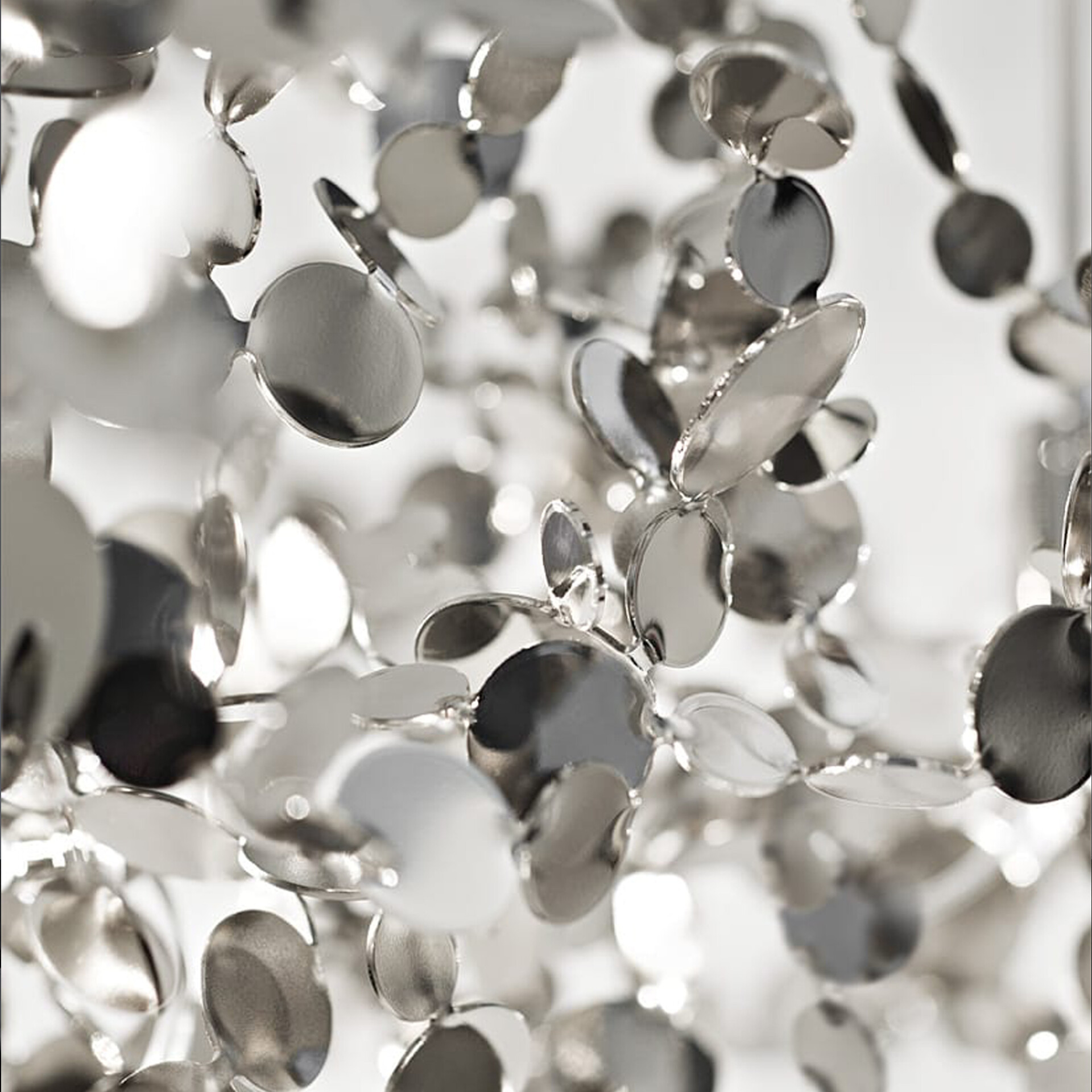 Close-up of numerous small, reflective silver discs linked together, creating a shimmering, abstract pattern with varying focus.