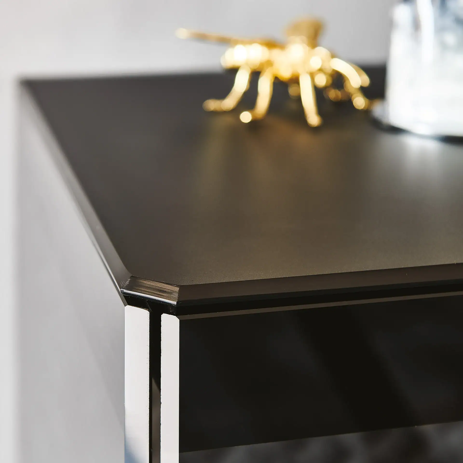 Close-up of a sleek black boutique sideboard with metallic accents.
