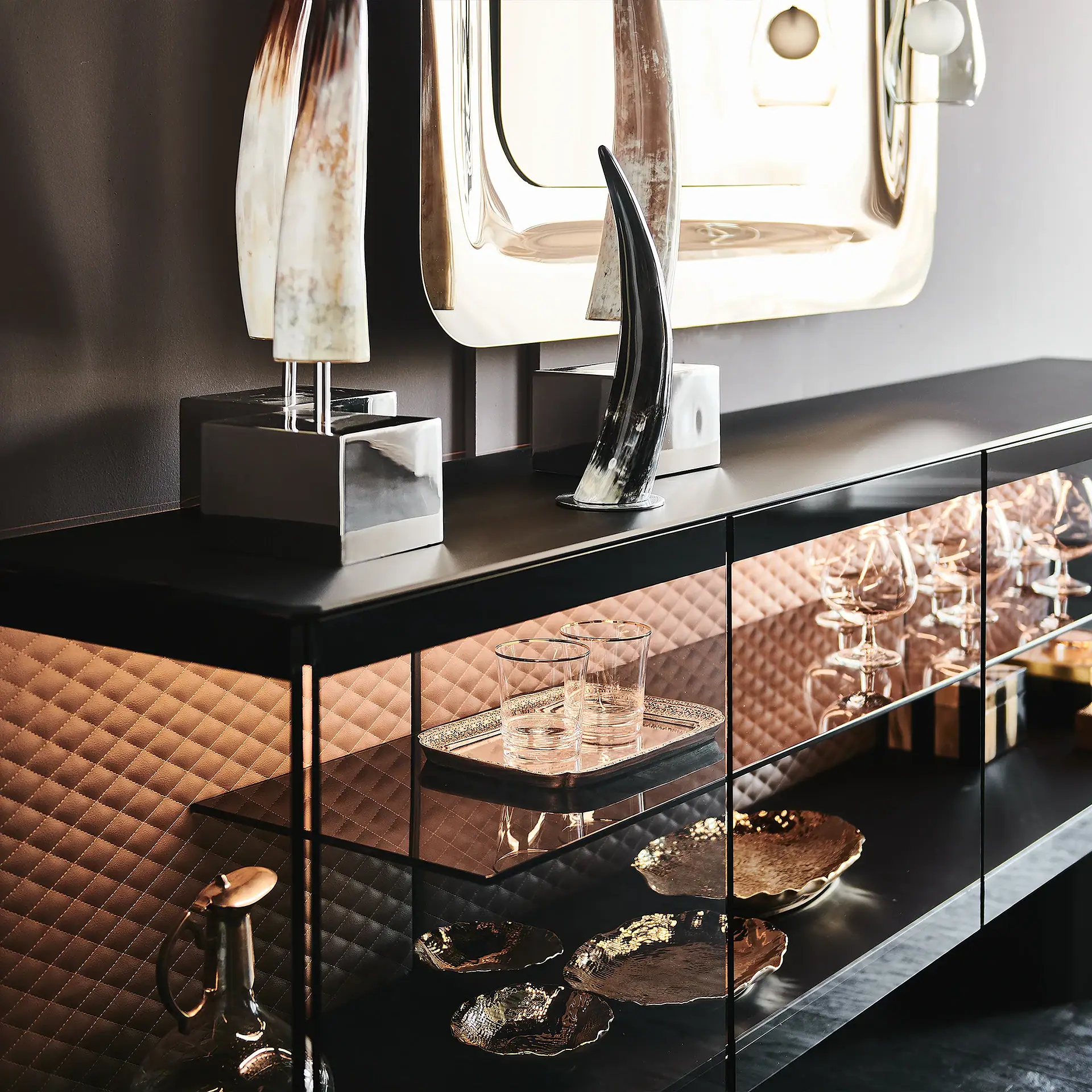 Contemporary sideboard with decorative sculptures and glassware.