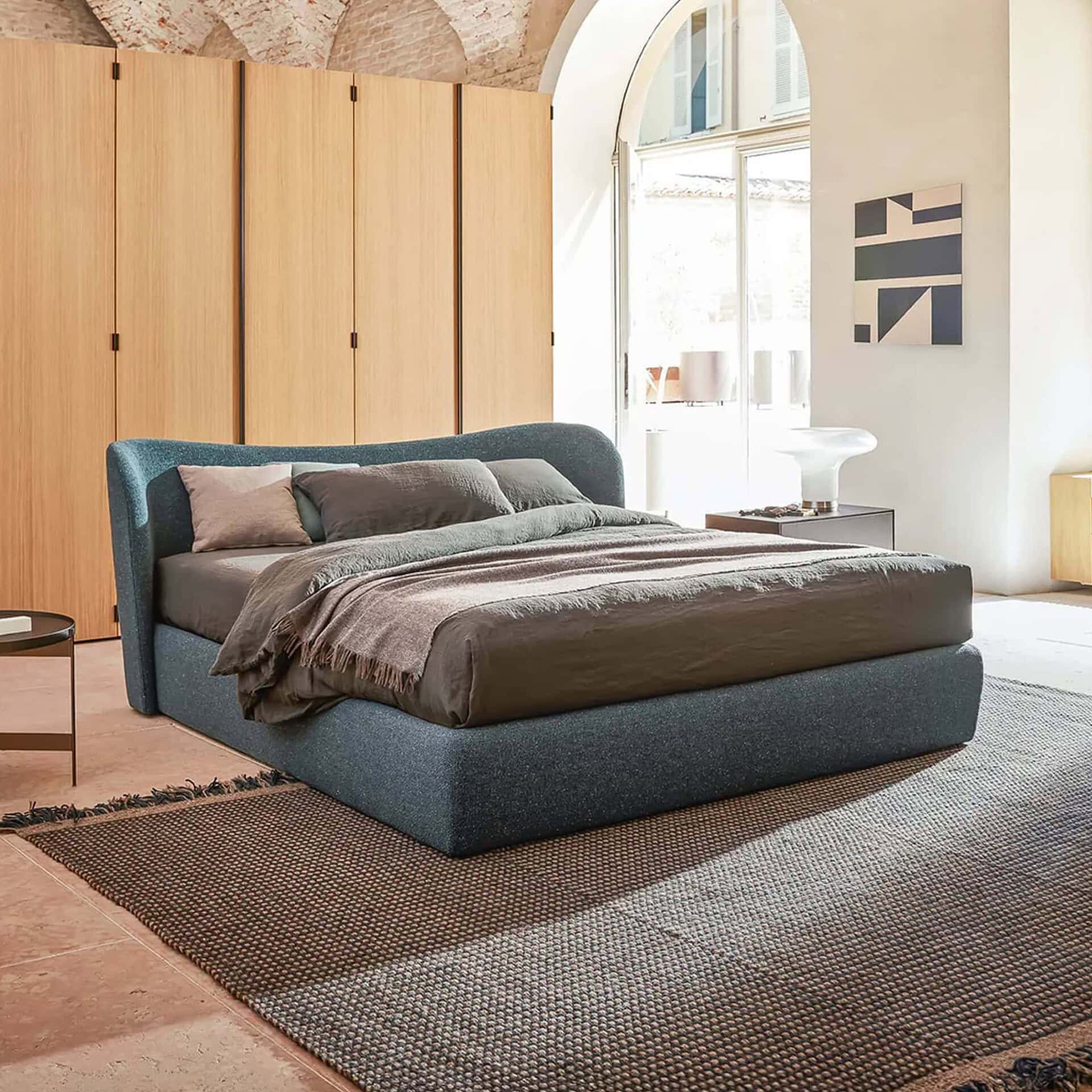 Elegant contemporary bedroom featuring a navy upholstered bed, wooden panels, and minimalist decor for a sophisticated look.