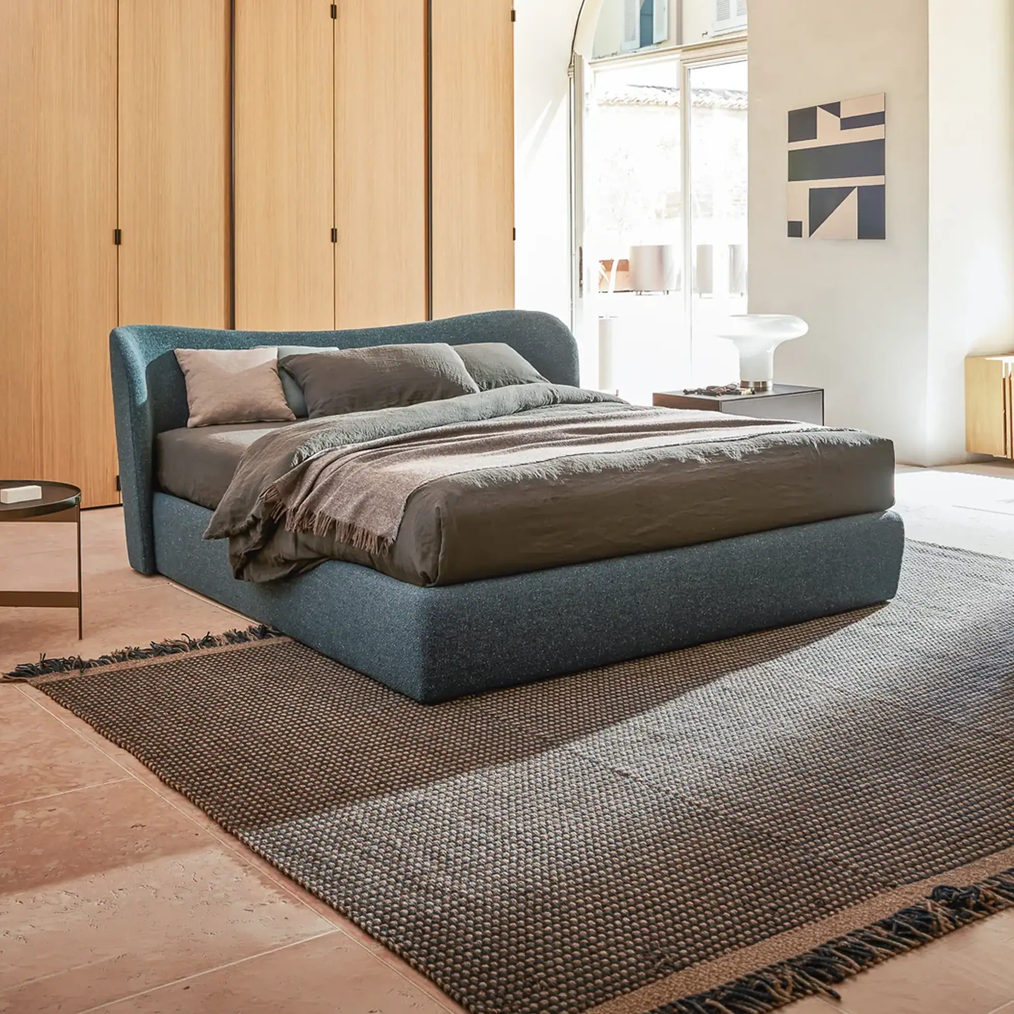 Elegant contemporary bedroom featuring a navy upholstered bed, wooden panels, and minimalist decor for a sophisticated look.