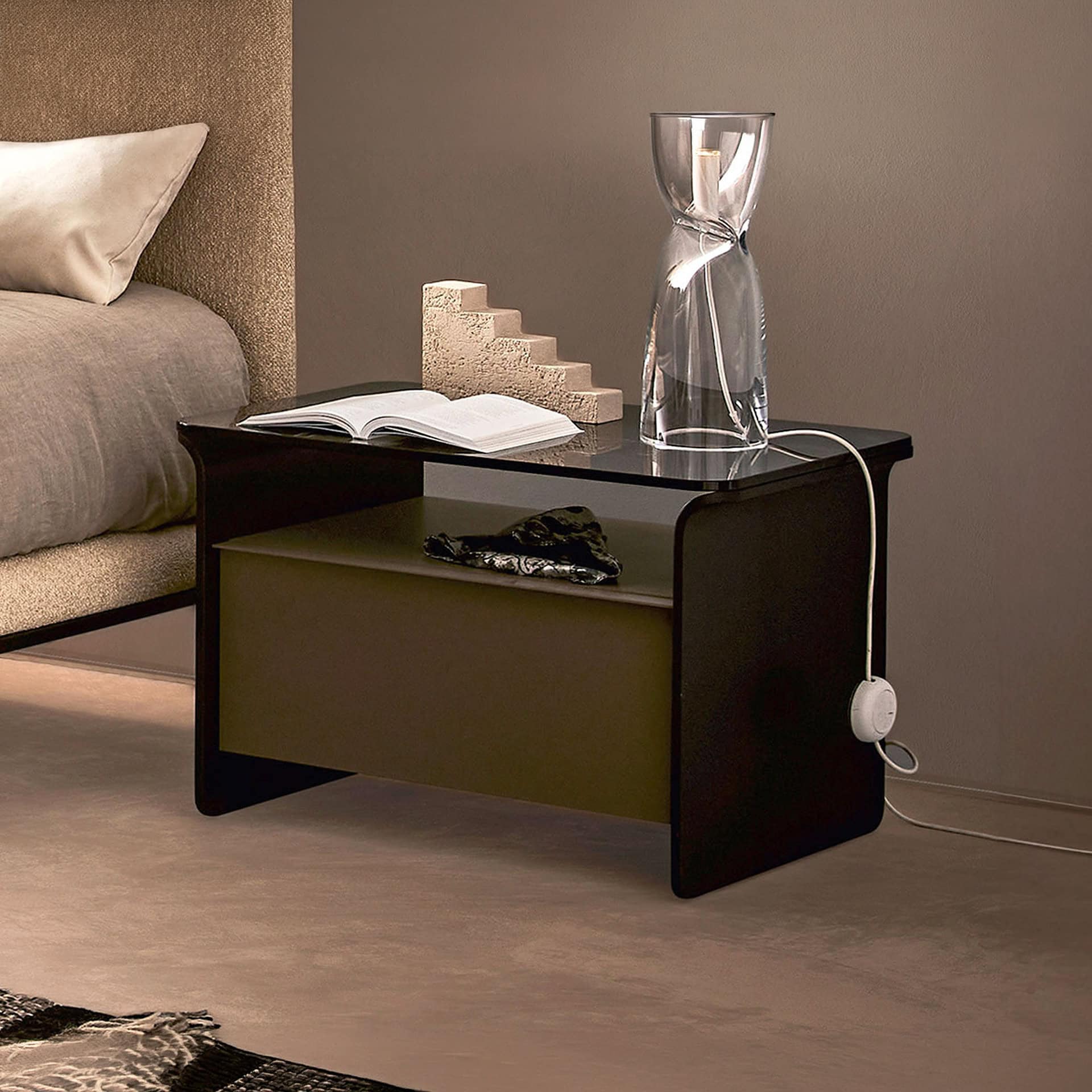 Contemporary black and olive nightstand with glass vase and decorative objects.