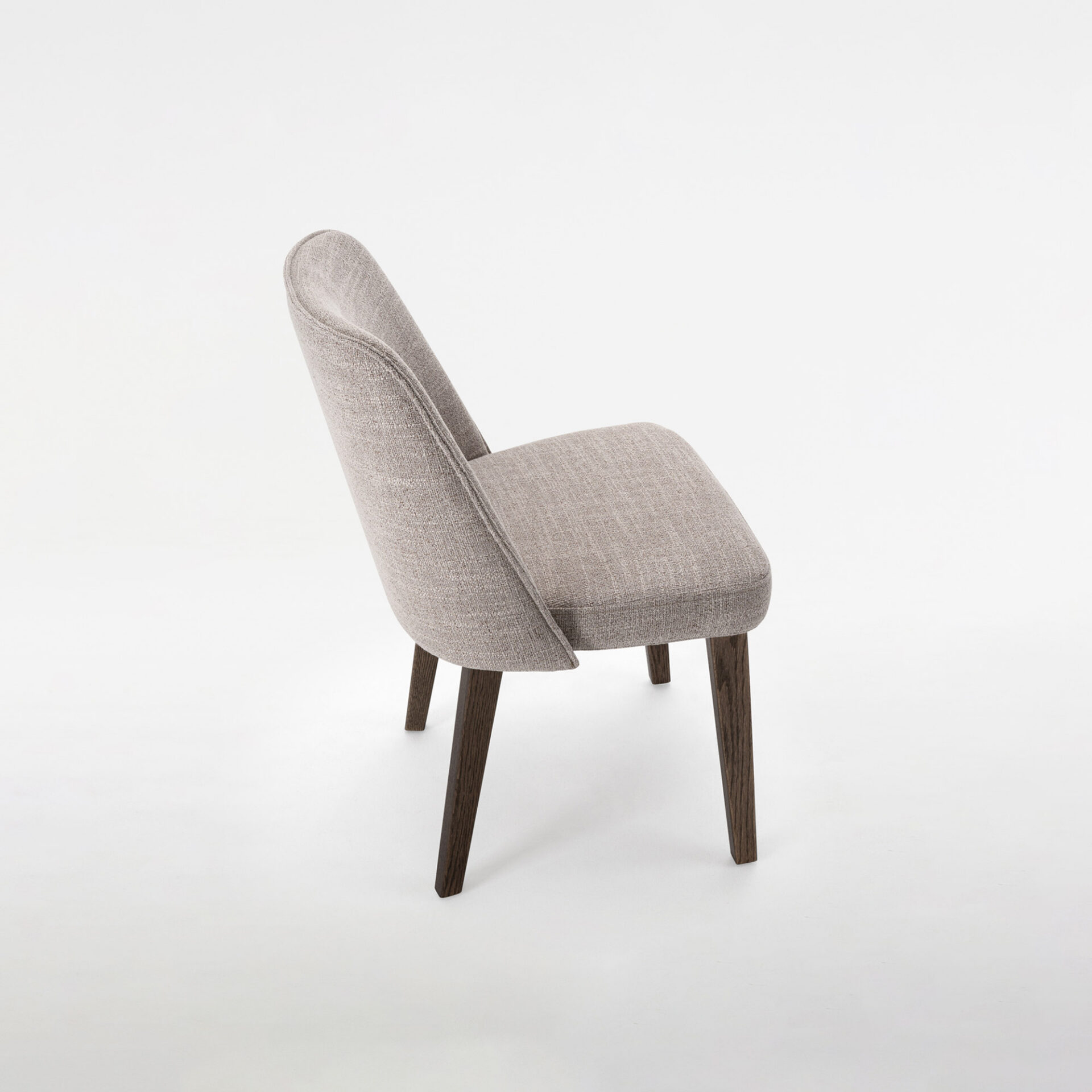 A modern, armless upholstered chair with light grey textured fabric and dark brown wooden legs, viewed from a three-quarter angle against a white background.