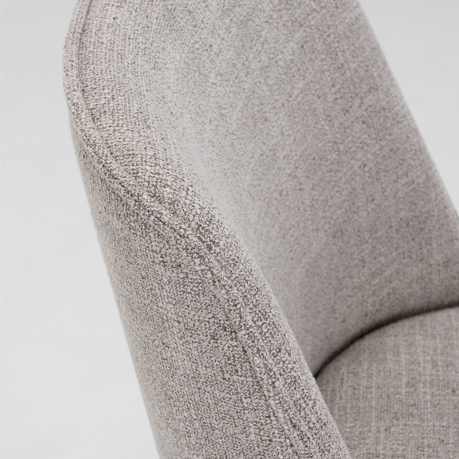 Close-up of light gray and brown heathered fabric upholstery with a visible seam along a soft curve, highlighting the textile's texture.