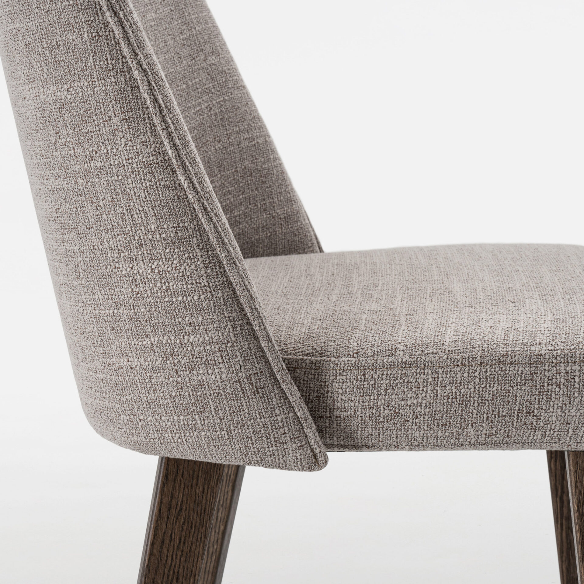 Close-up of a modern greige upholstered chair with a textured fabric and dark brown wooden legs, against a light background.