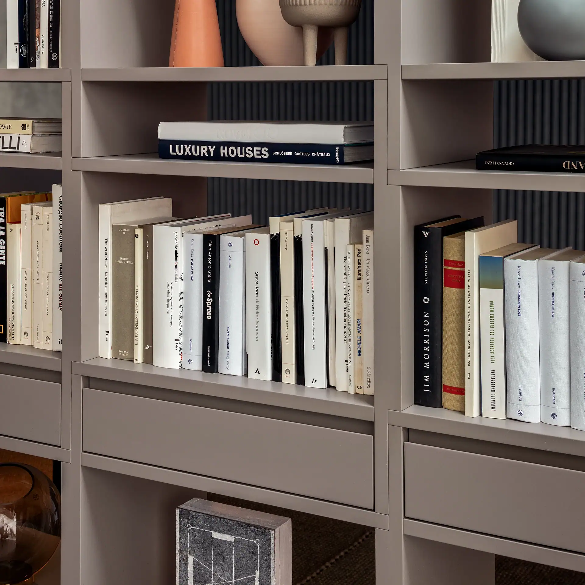 Books arranged on grey modular shelving unit with decorative items.