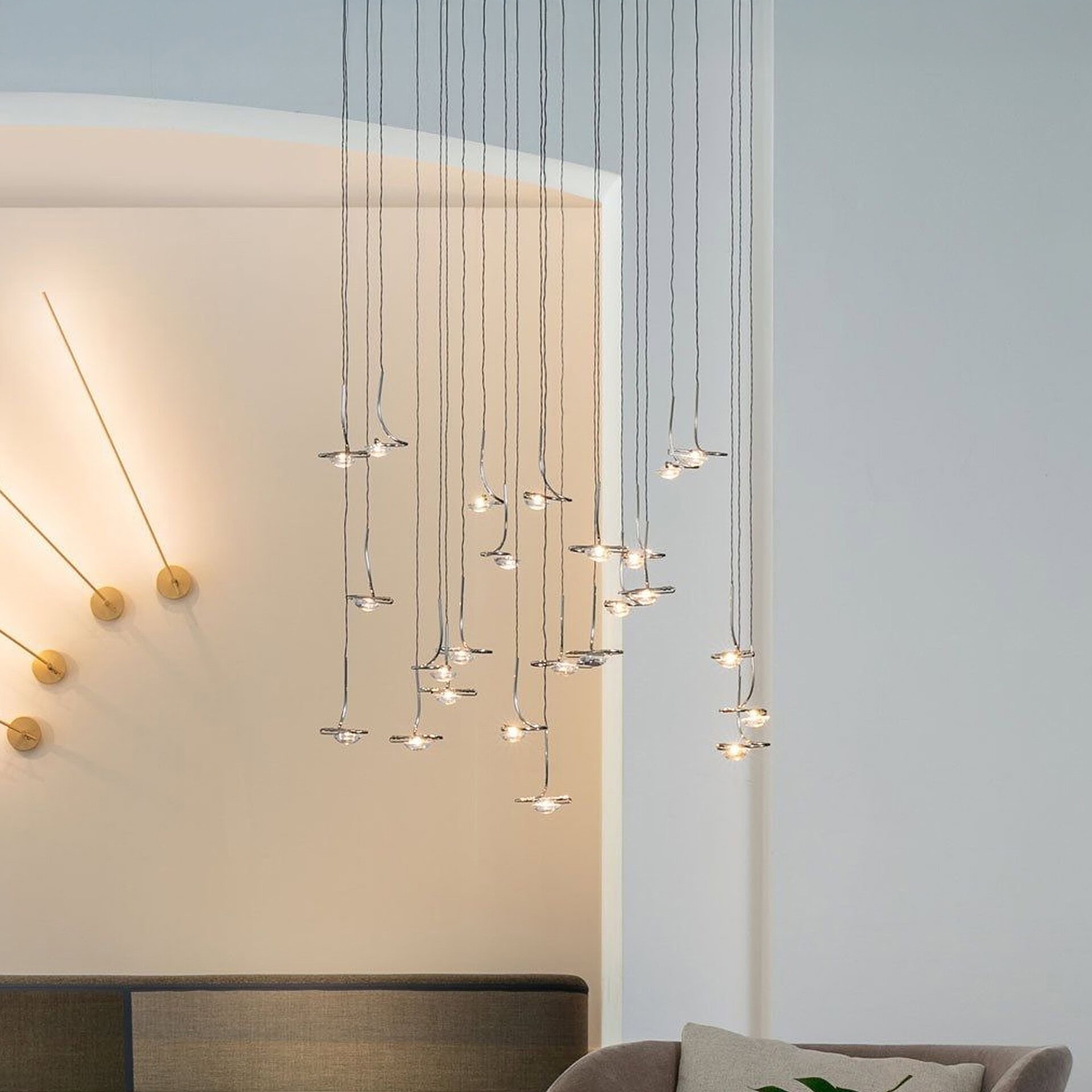 Jackie O chandelier featured in a living space, softly illuminating the room with cascading glass pendants and blue suspension wires.