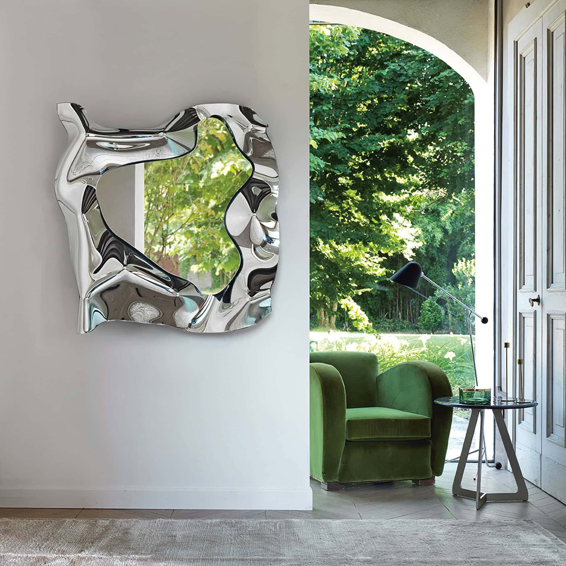 Christine Mirror in vertical format displayed on a living room wall beside green accent chair.