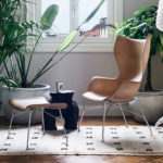 Contemporary Scandinavian-inspired living space with wooden chairs, lush plants, and decorative lighting.