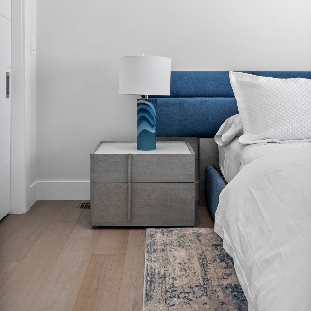 a bed with a blue headboard and a lamp