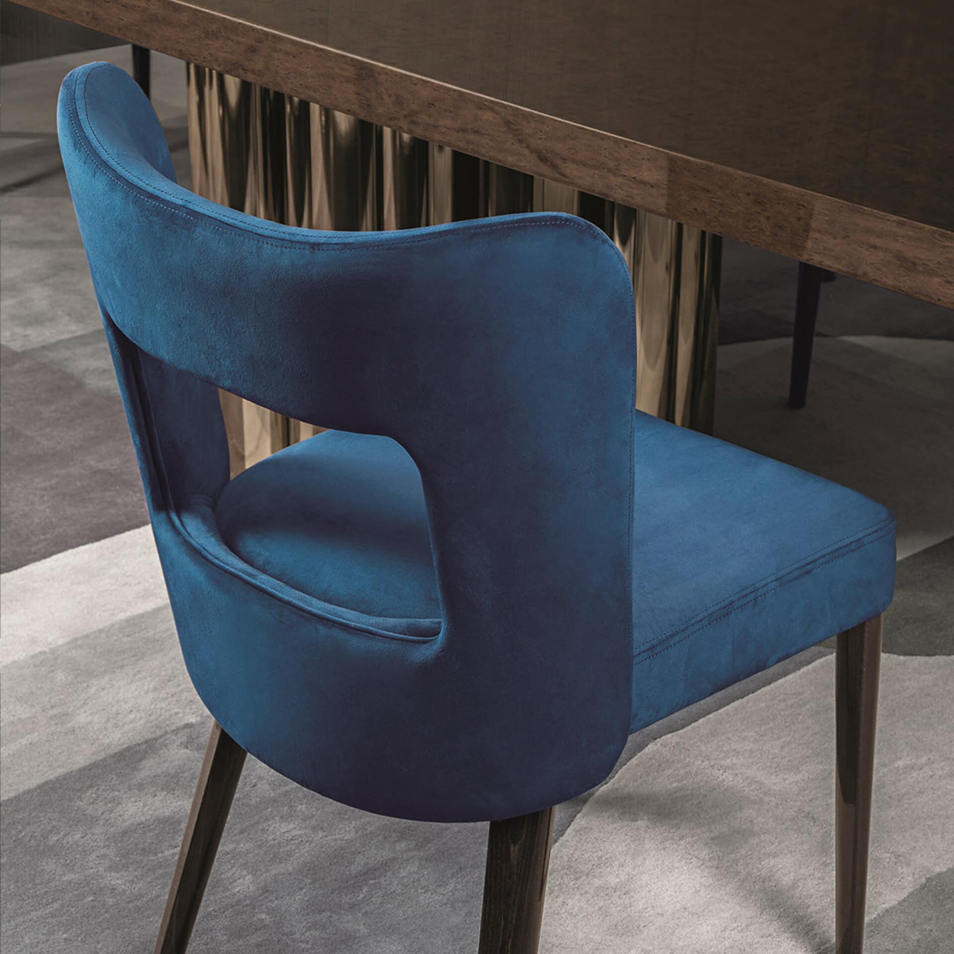 Stylish blue velvet dining chair with wooden legs for modern interiors.