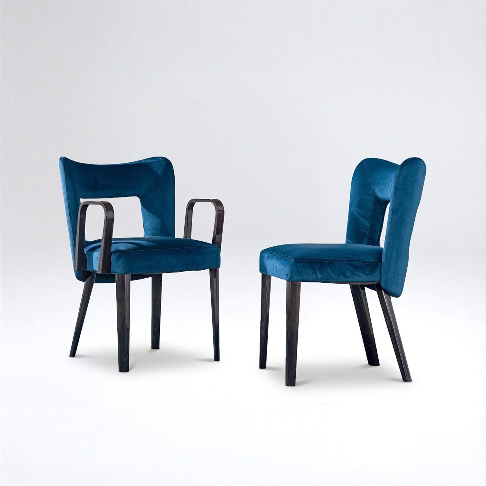 Blue velvet dining chairs with armrests and dark wood legs for modern interiors.