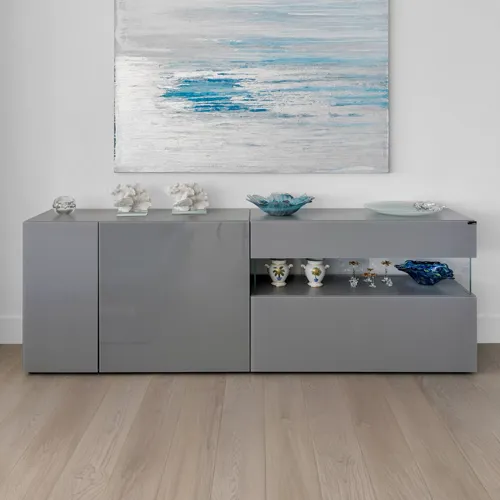 A modern gray sideboard with decorative items, beneath a blue and white abstract painting, on a light wooden floor.