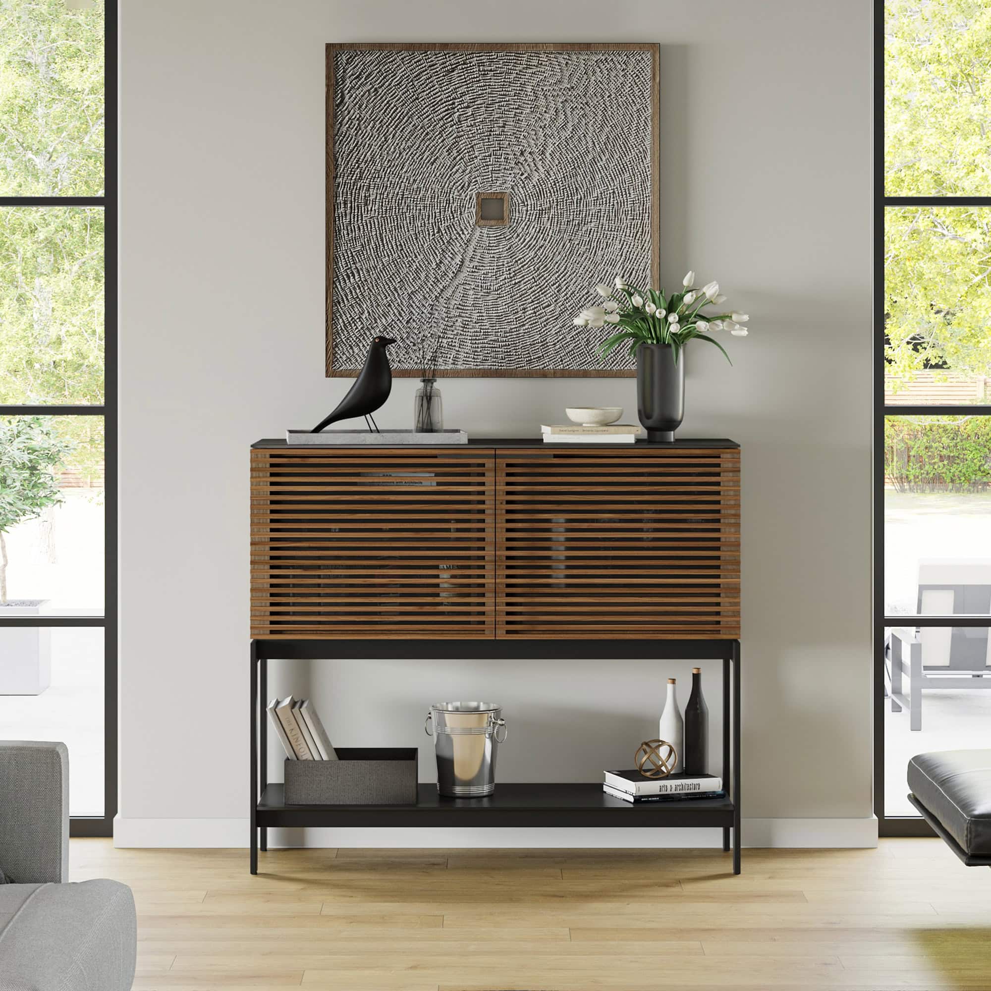 Contemporary wooden sideboard with black metal frame, decorative objects, and floral arrangement.