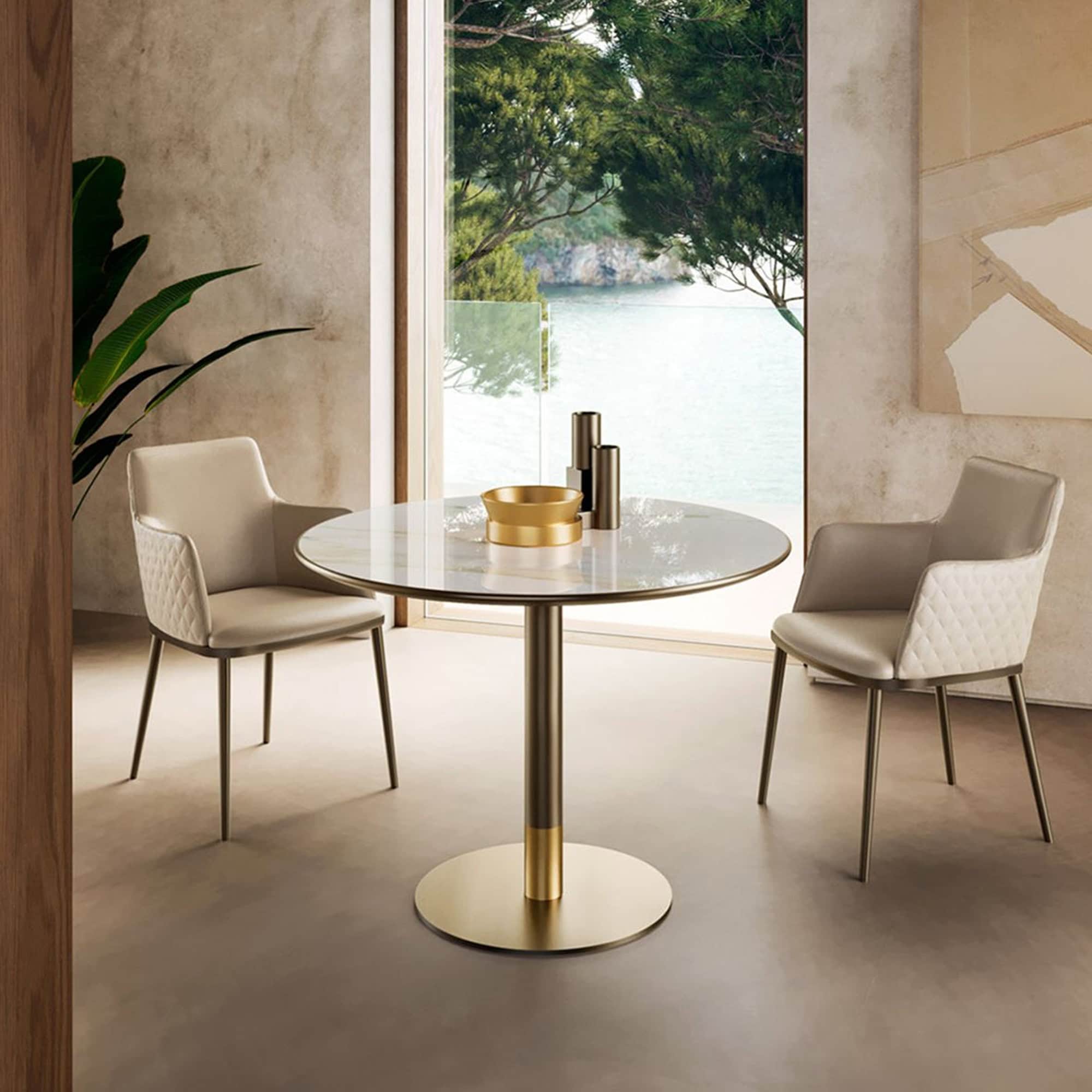 Cilindro Bistro Table with gold base and round ceramic top styled in a modern dining setting.