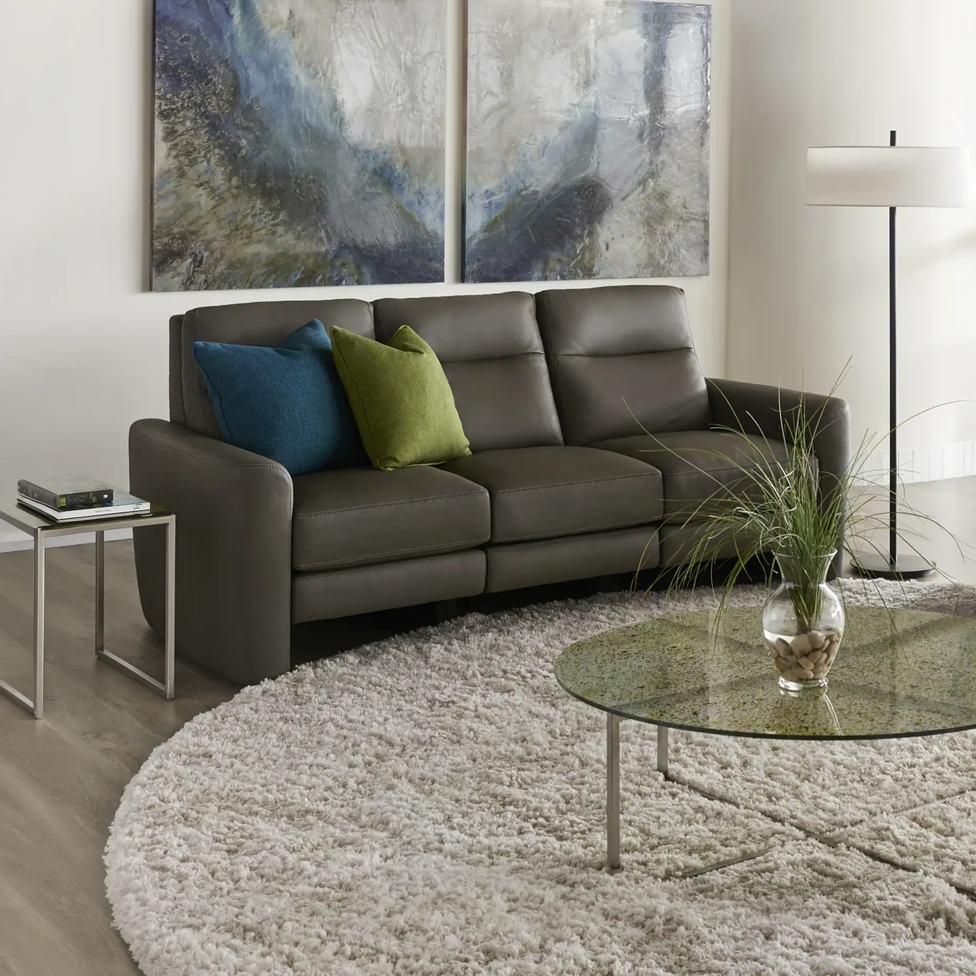 Modern gray leather sofa with blue and green accent pillows in a contemporary living room.