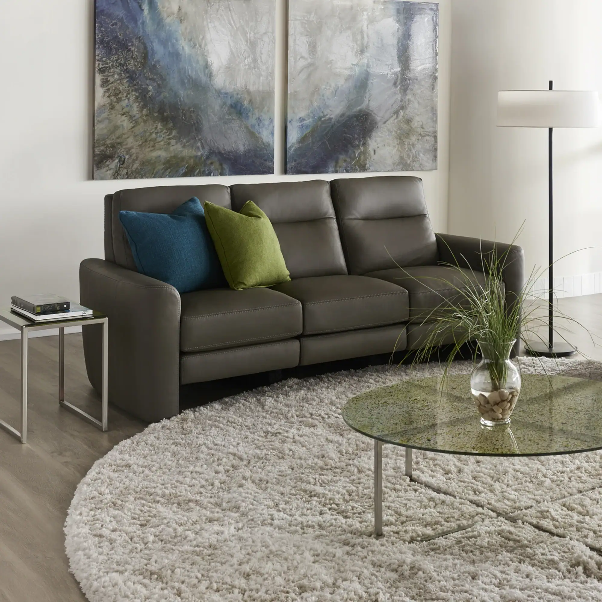Modern gray leather sofa with blue and green accent pillows in a contemporary living room.