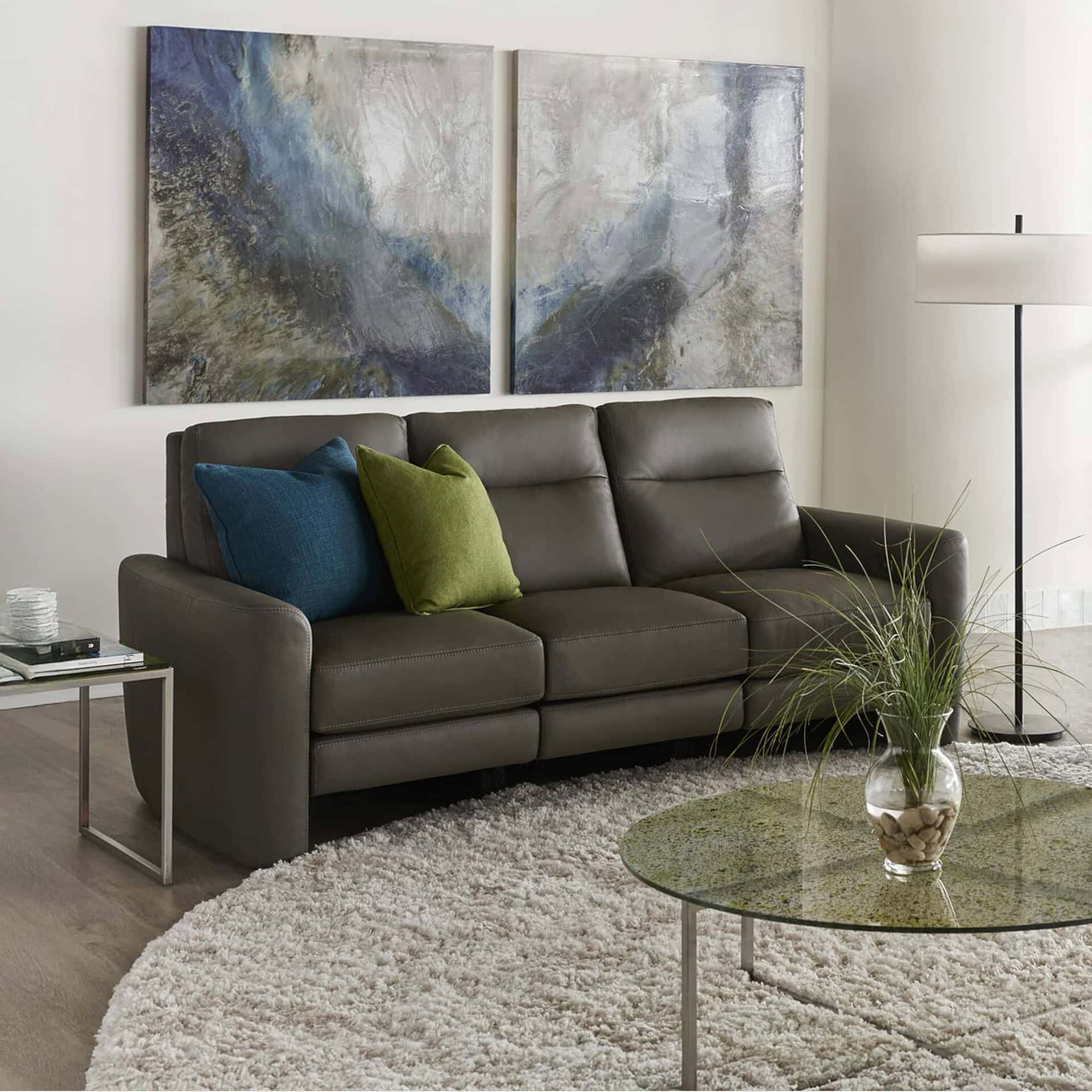Modern gray leather sofa with blue and green accent pillows in a contemporary living room.