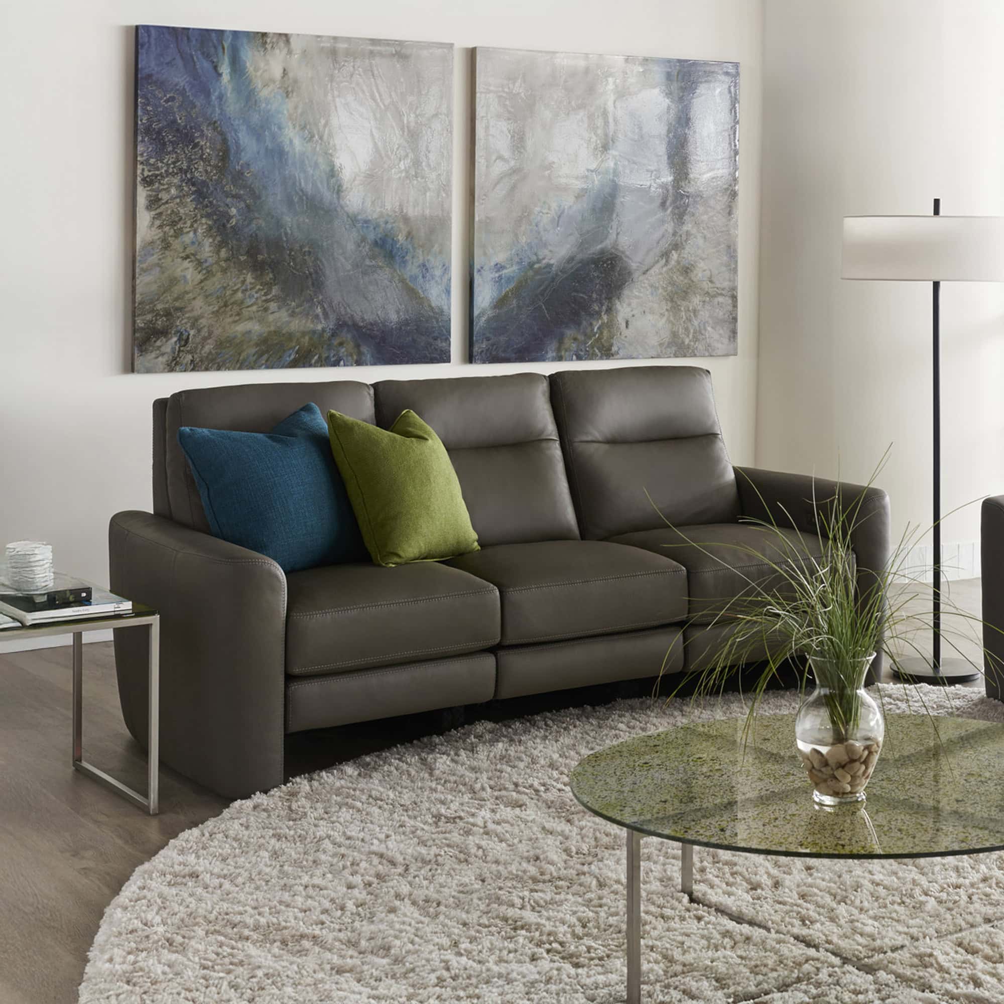 Modern gray leather sofa with blue and green accent pillows in a contemporary living room.