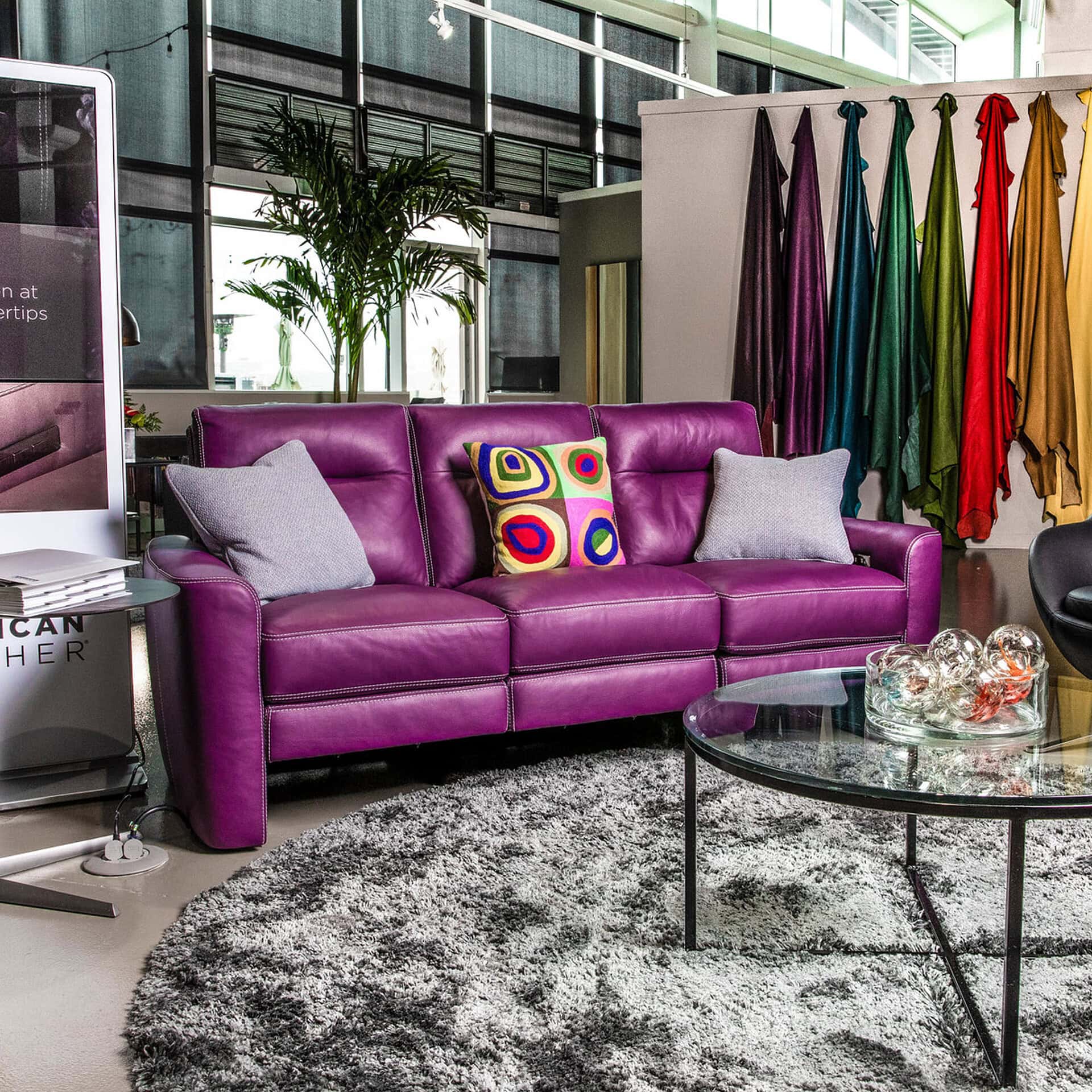 Purple sofa with colorful pillows in a modern showroom setting.