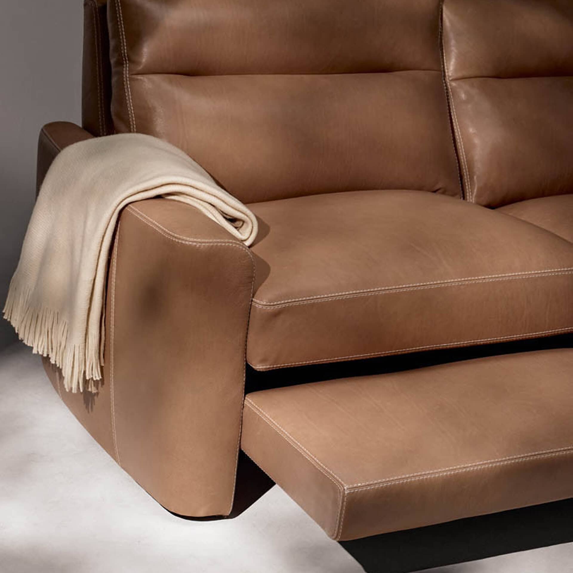 Reclining leather sofa with adjustable footrest and plush cushions for comfort. Perfect for modern l.