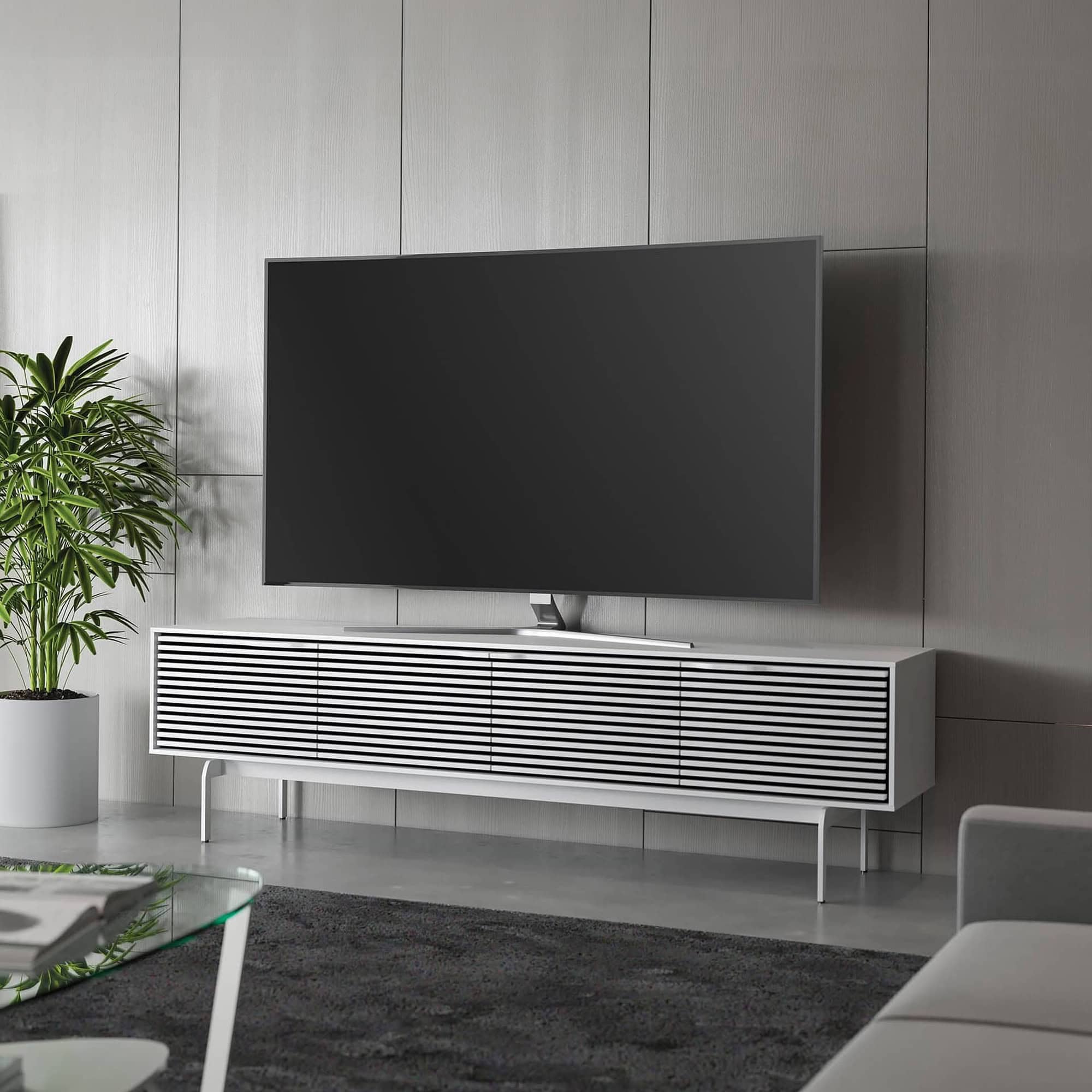 Modern white media console with slatted design for stylish TV setup and storage.