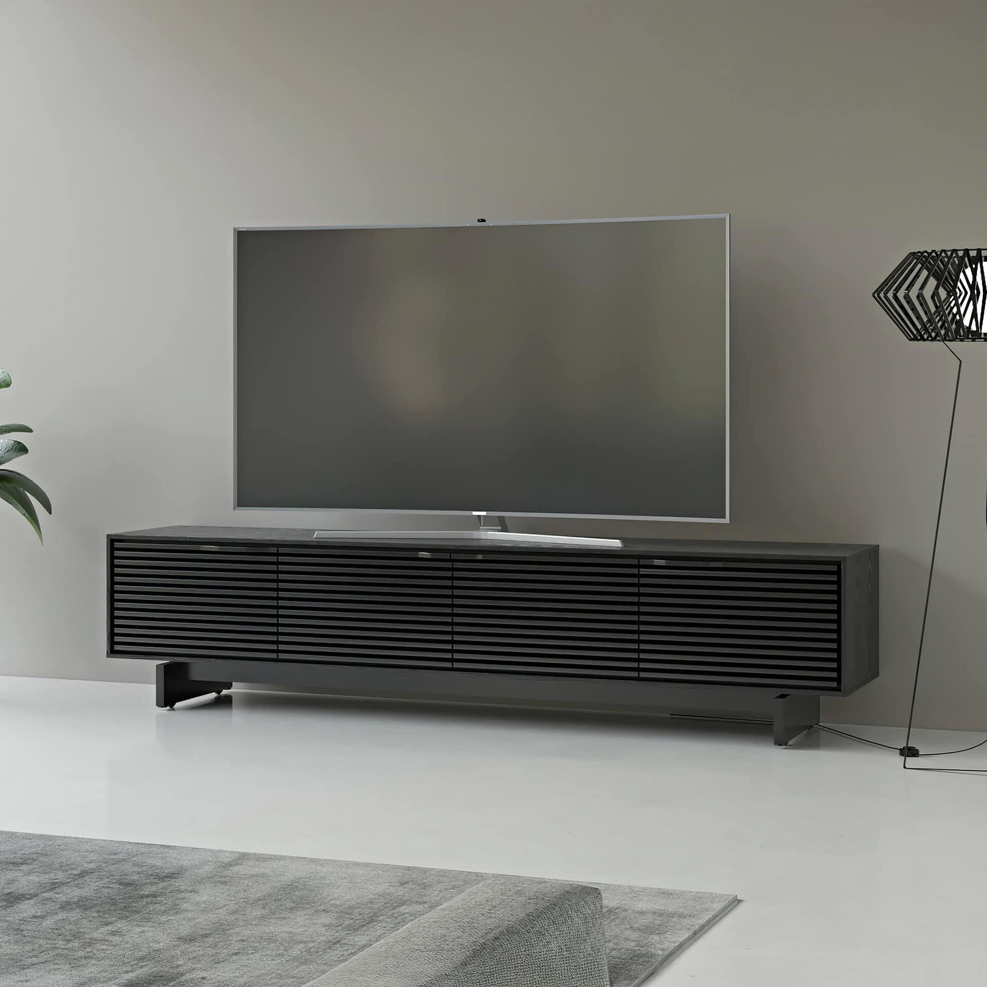Sleek black modern TV media console with slatted doors for a minimalist living room style.