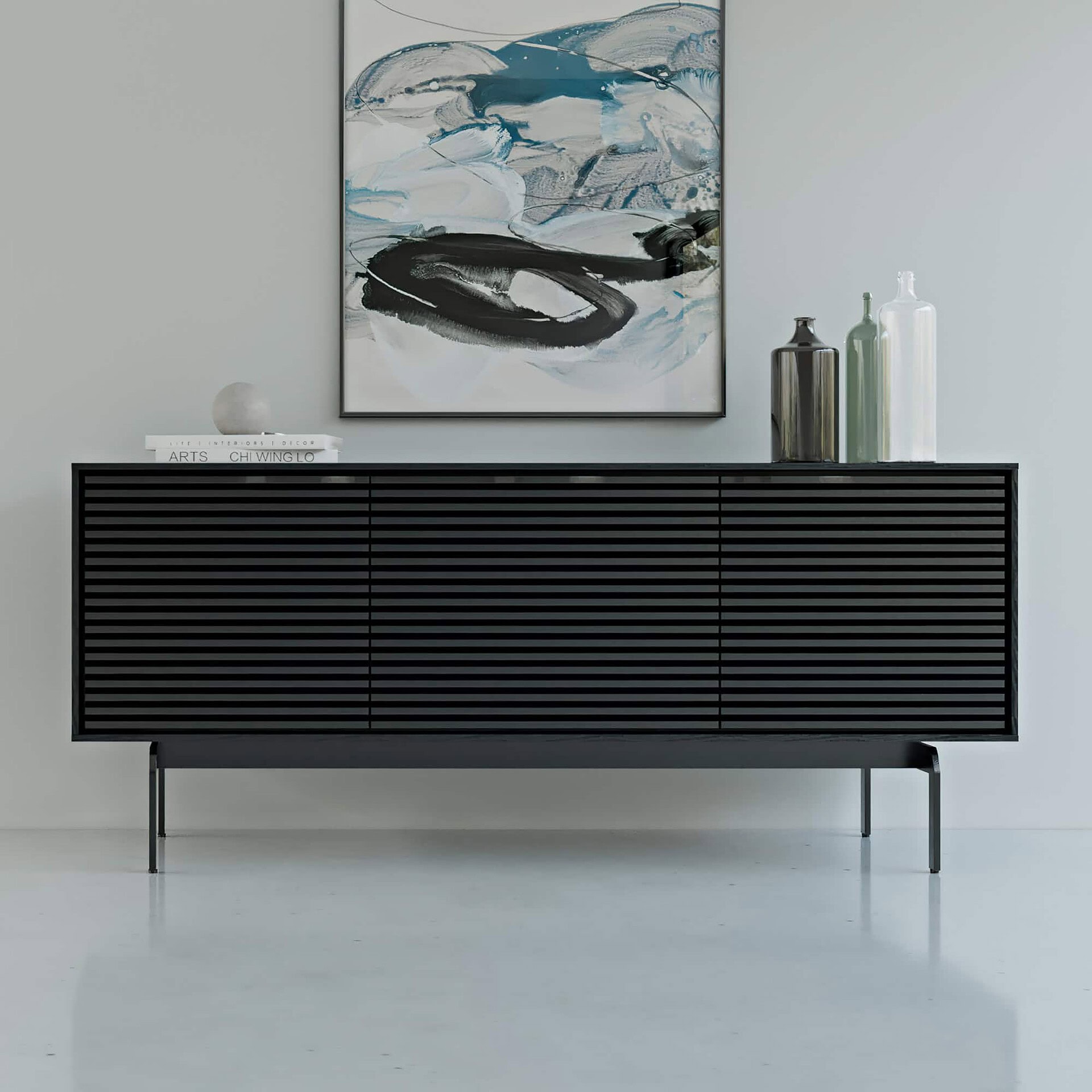 Black BDI Align 7477 media console with louvered doors styled with modern artwork.