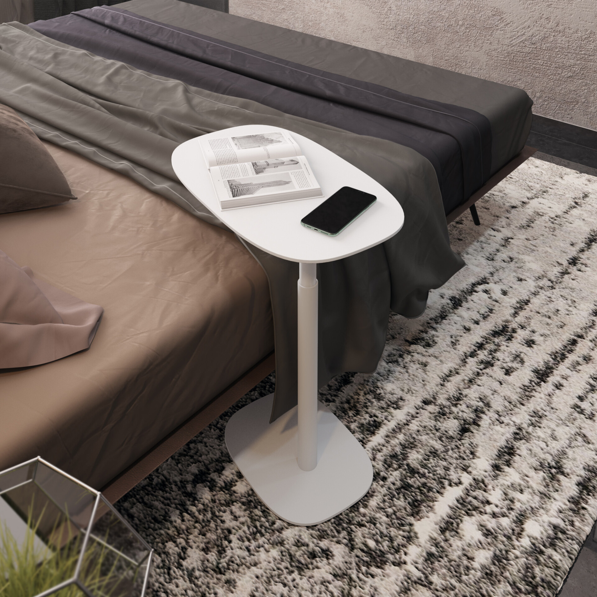 A white adjustable side table next to a bed with an open book and a black smartphone on its surface. The bed has neutral-toned bedding, and the floor is covered by a shaggy black and white rug.