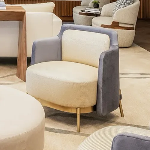 A modern armchair with a blue velvet back and a beige herringbone seat, on a light rug with gold legs.