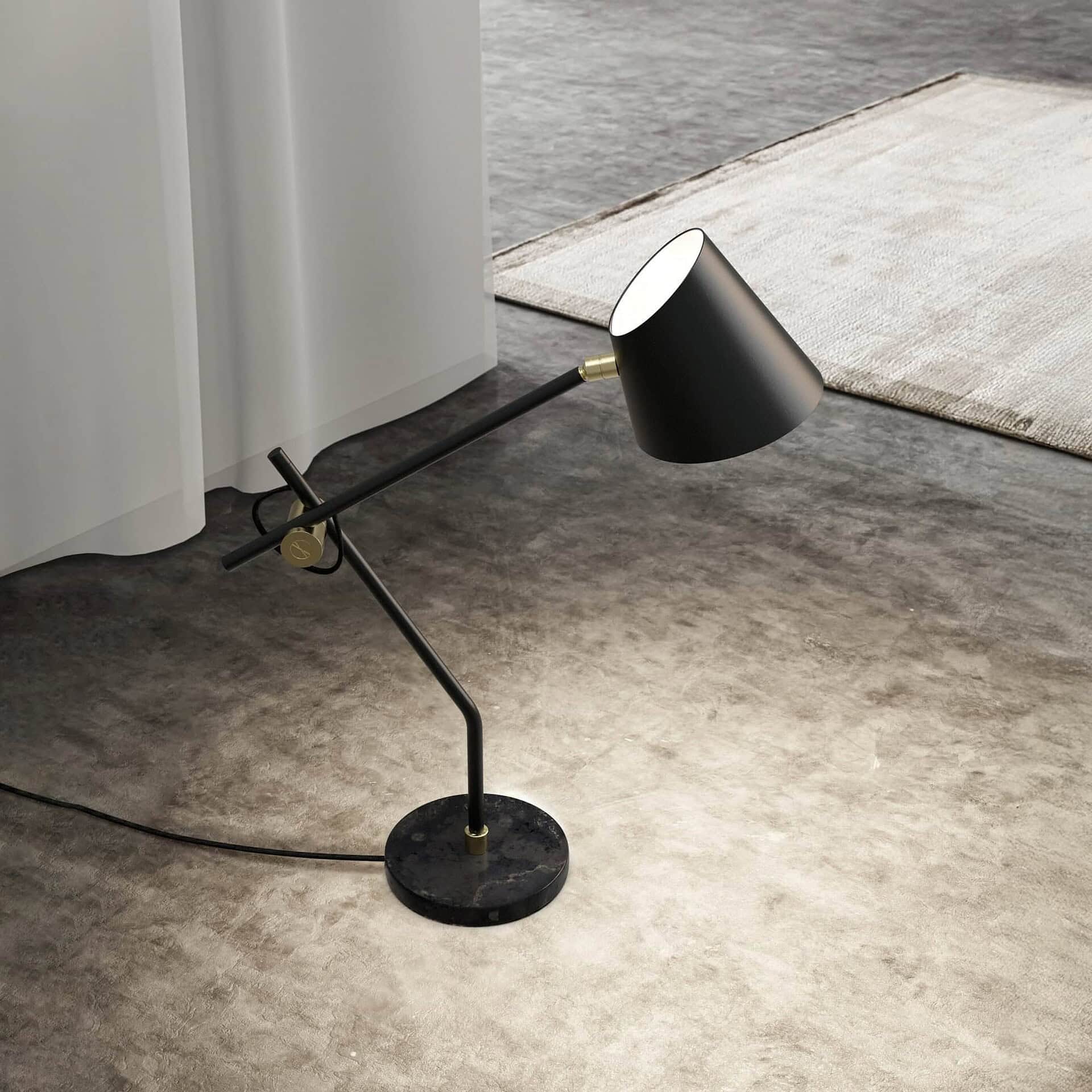 Sleek black modern desk lamp with brass accents on a textured floor and area rug.