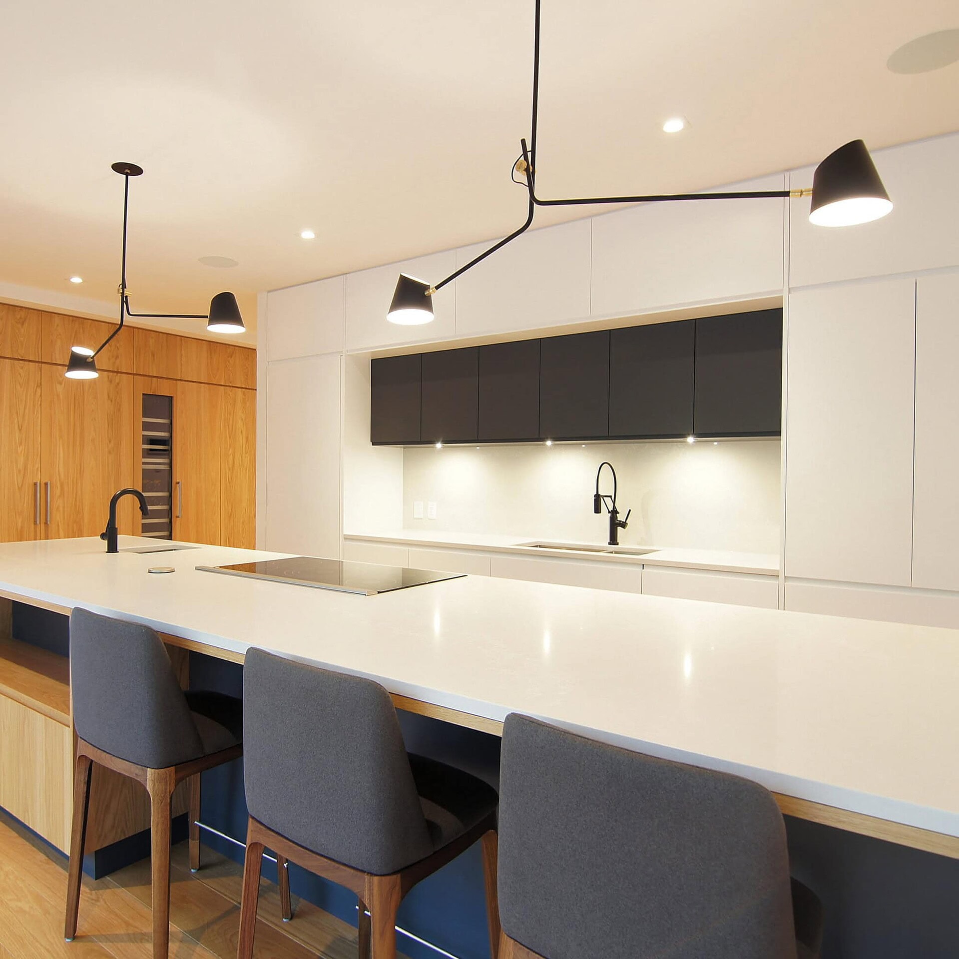 Modern kitchen with sleek black and white cabinetry, spacious island, and stylish lighting fixtures.