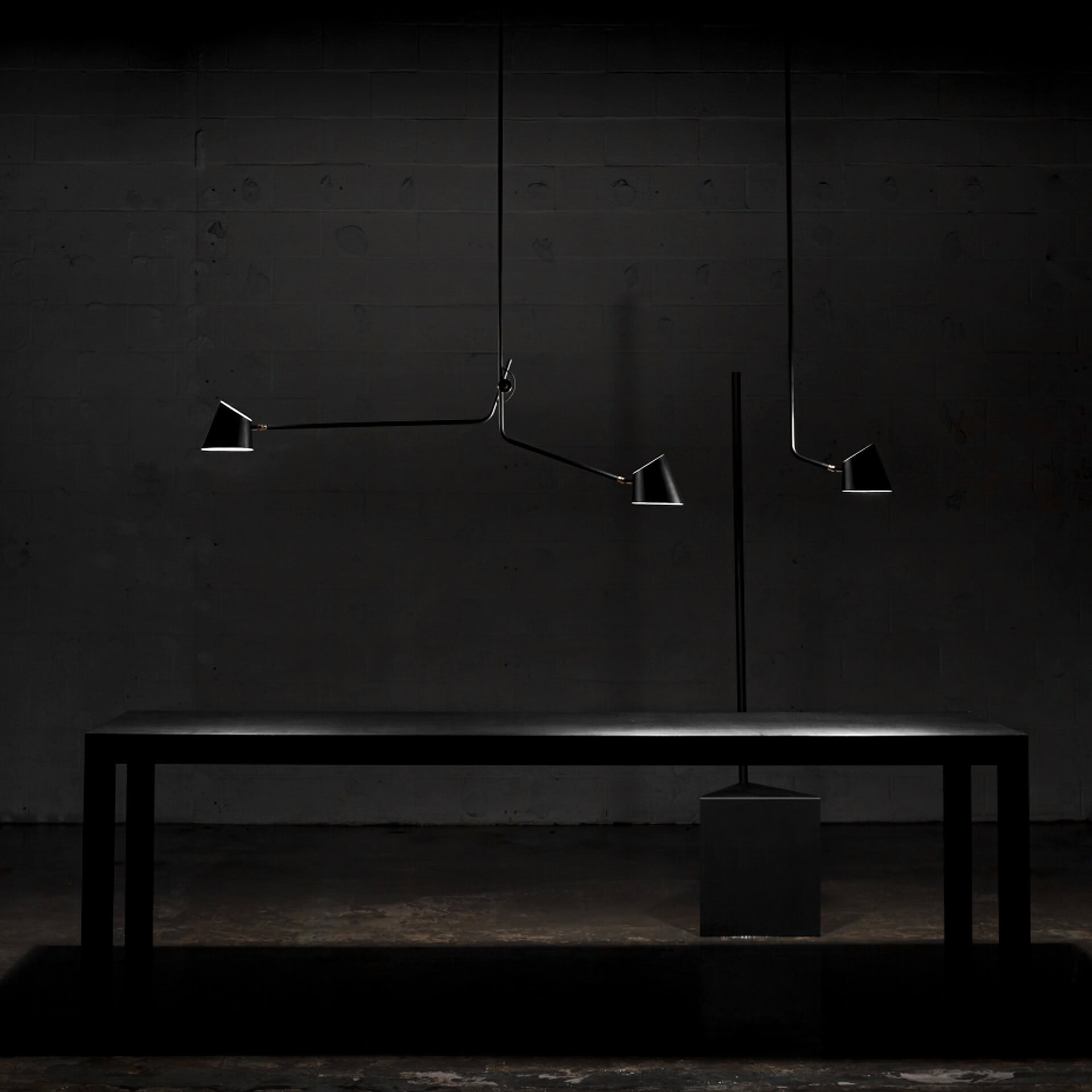 Sleek black modern pendant lighting over minimalist black table against dark wall.