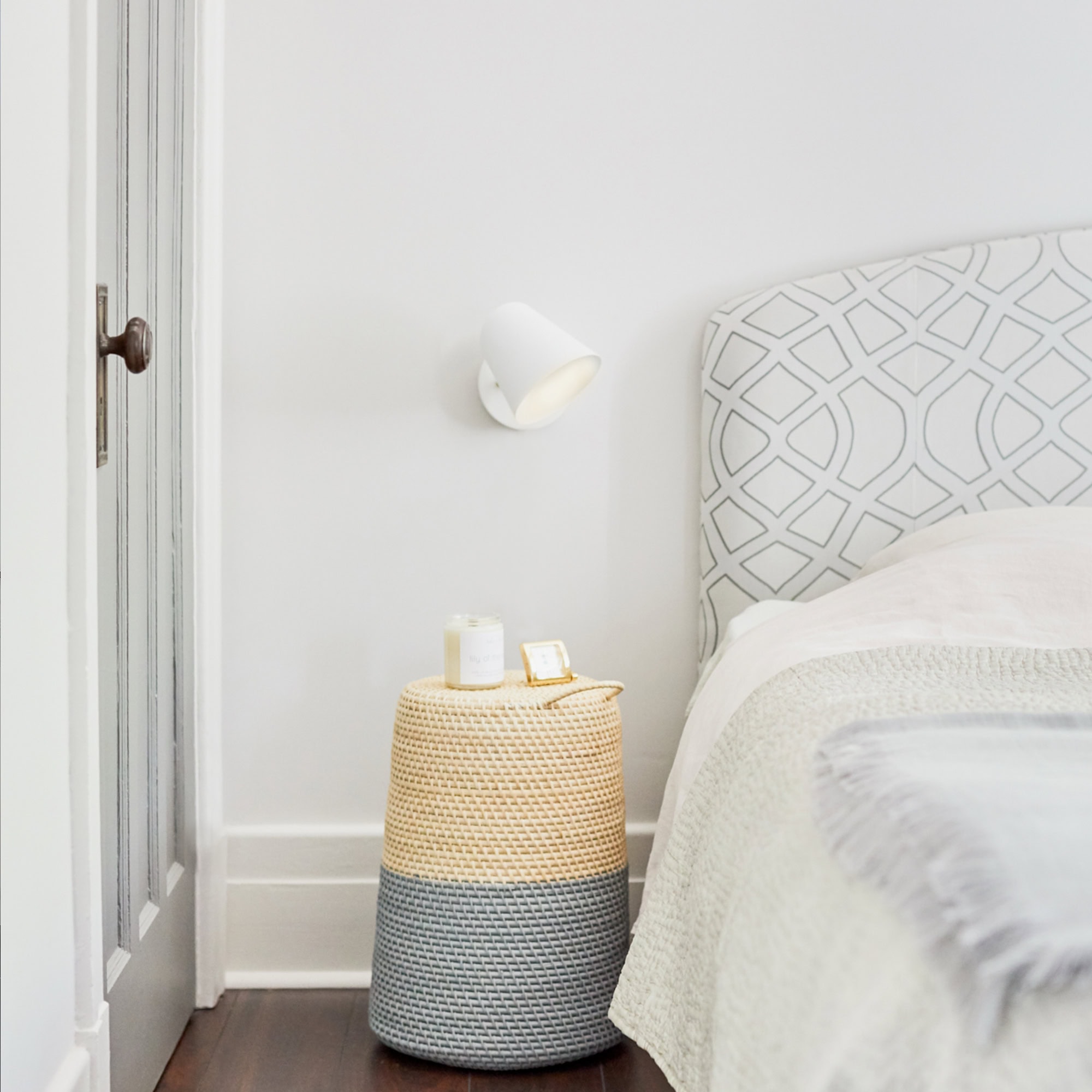 Elegant bedroom with stylish headboard, cozy bedding, and modern wall-mounted lamp from Sklar Furnishings.