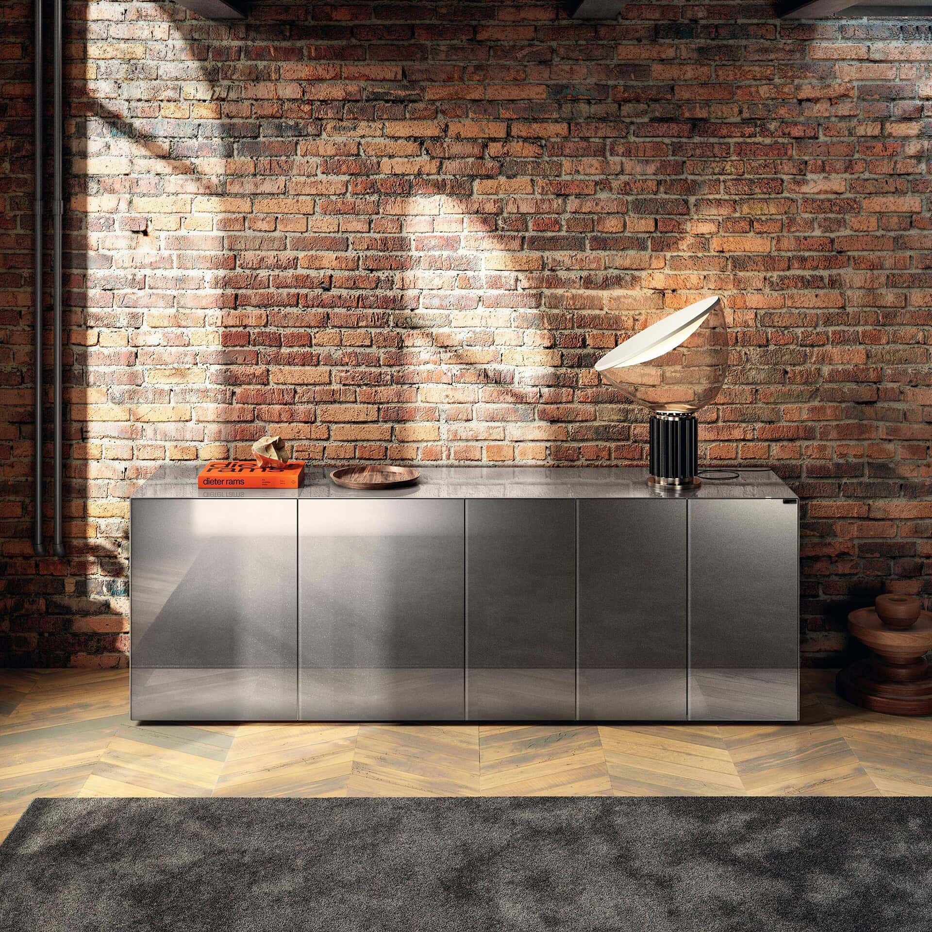 Stainless steel sideboard with decorative items against brick wall.