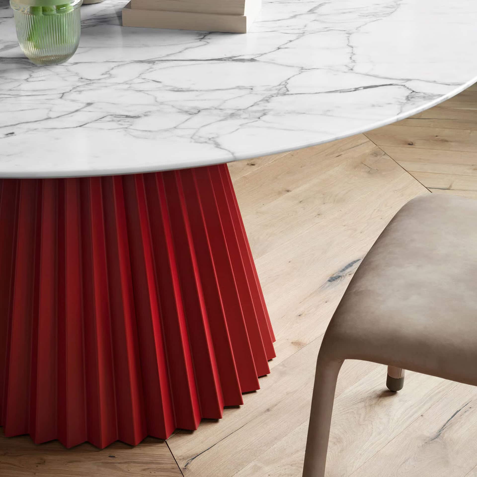 Modern round dining table with a plissé red base and marble top, stylish for contemporary dining spa.