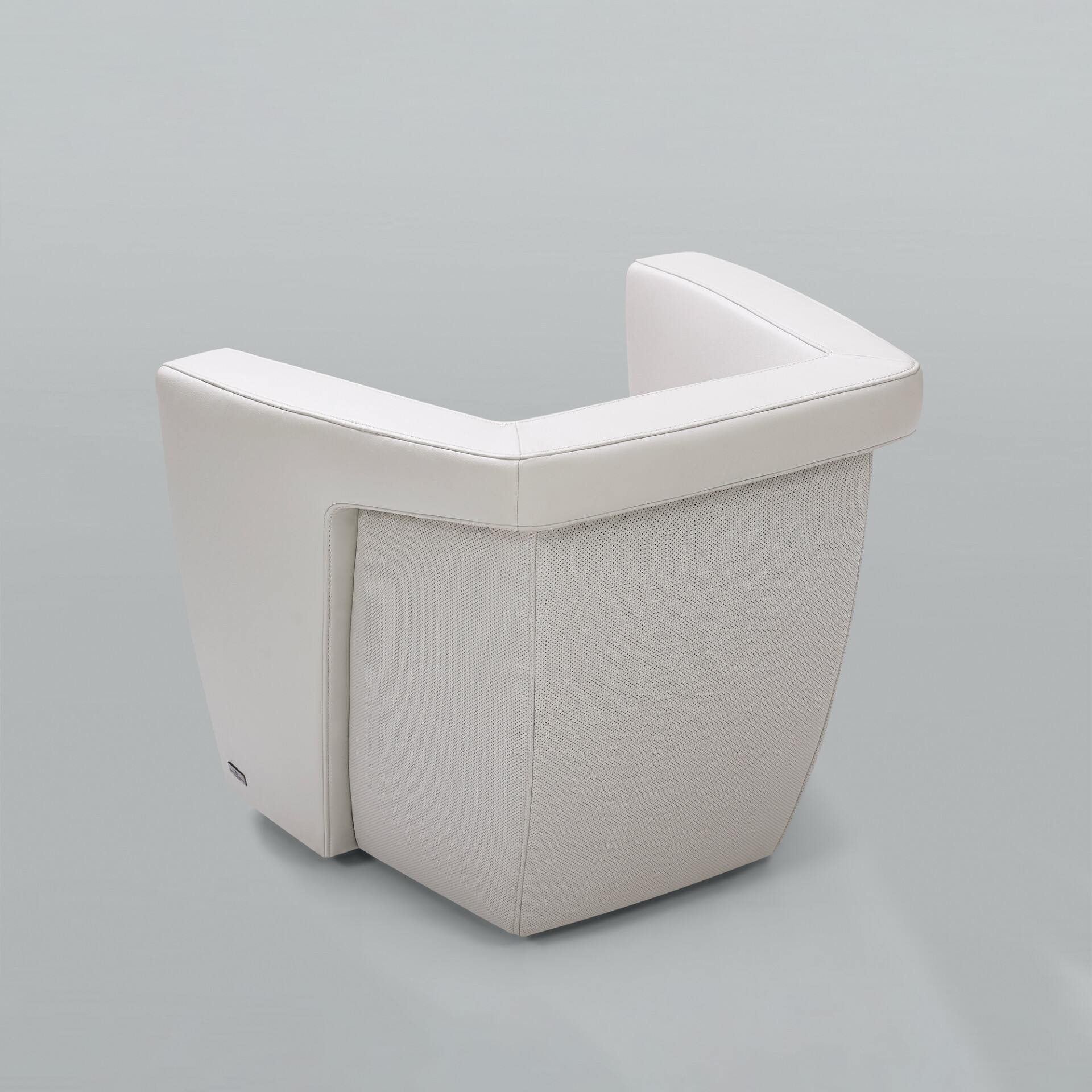 A light grey modern armchair with a smooth outer frame and perforated side panels, viewed from a three-quarter rear angle against a grey background.