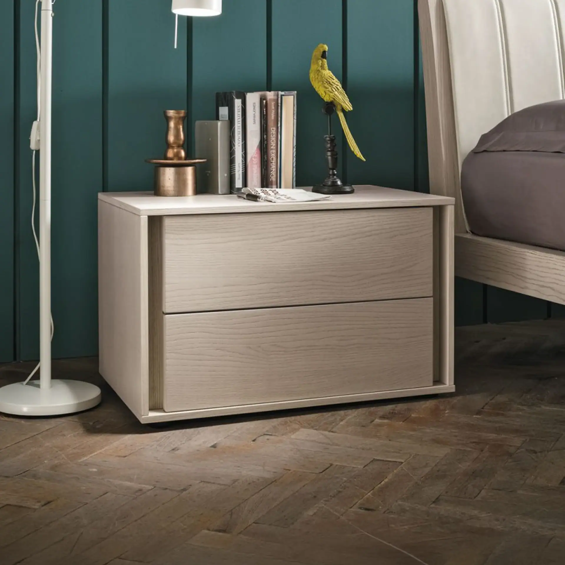 Modern white nightstand with decorative bird figurine and books in bedroom setting.