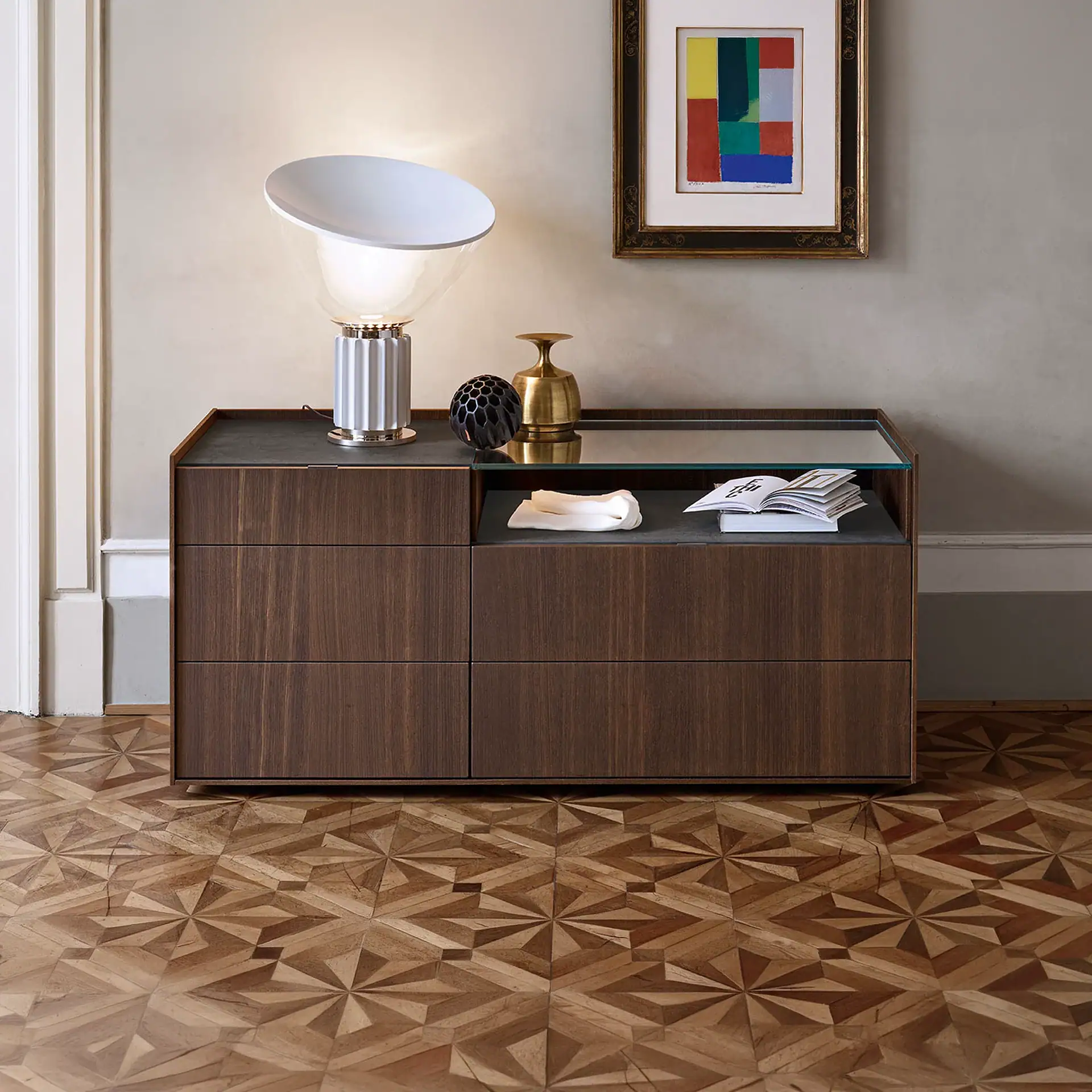 Elegant wooden sideboard with decorative vases, a lamp, and artwork in a contemporary living space.