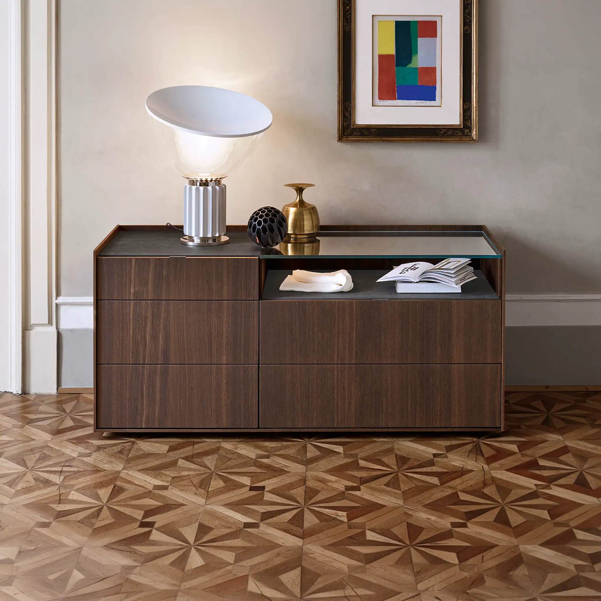 Elegant wooden sideboard with decorative vases, a lamp, and artwork in a contemporary living space.