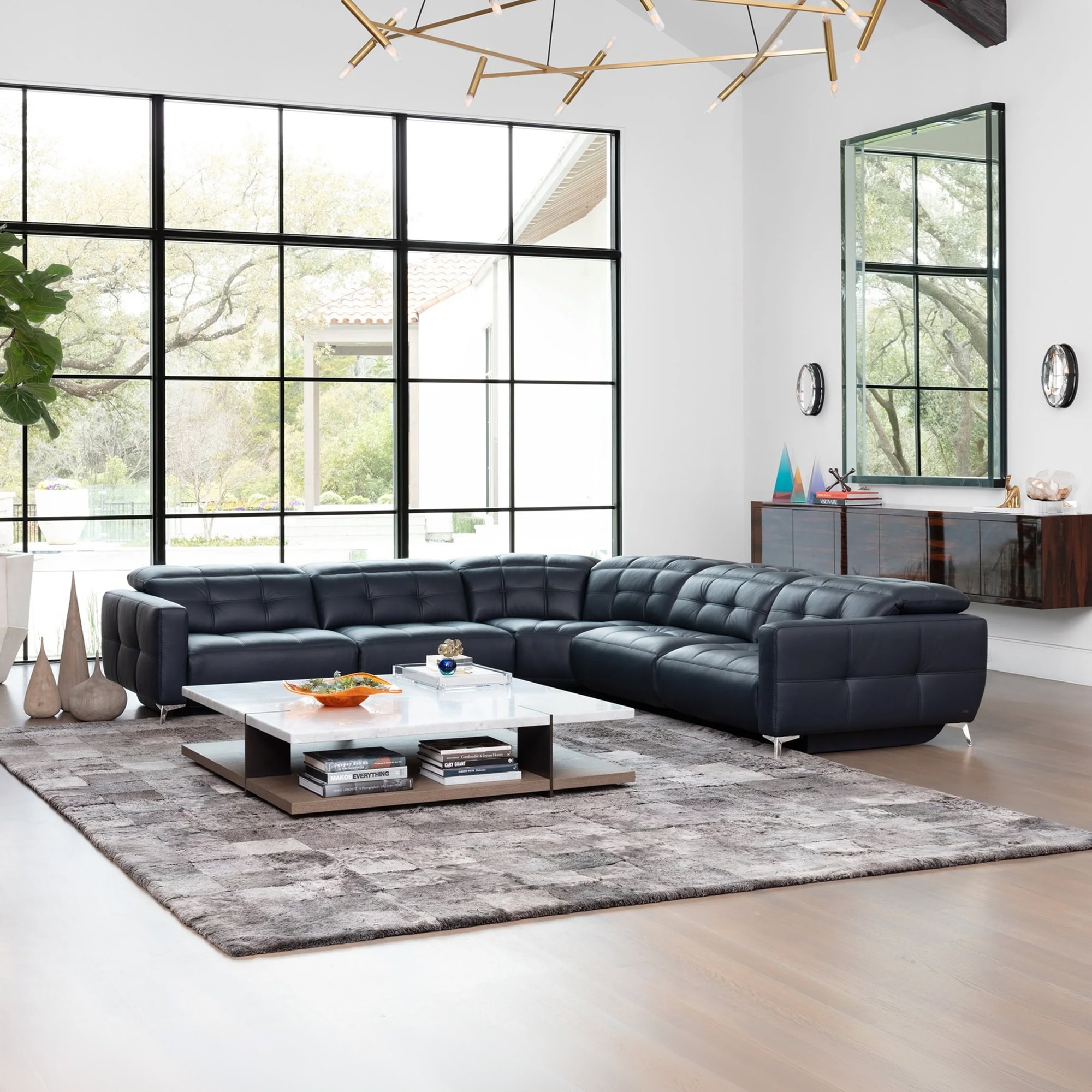 Verona Modular Motion Sectional Sofa in black leather, styled in a modern living room with large windows and contemporary décor.