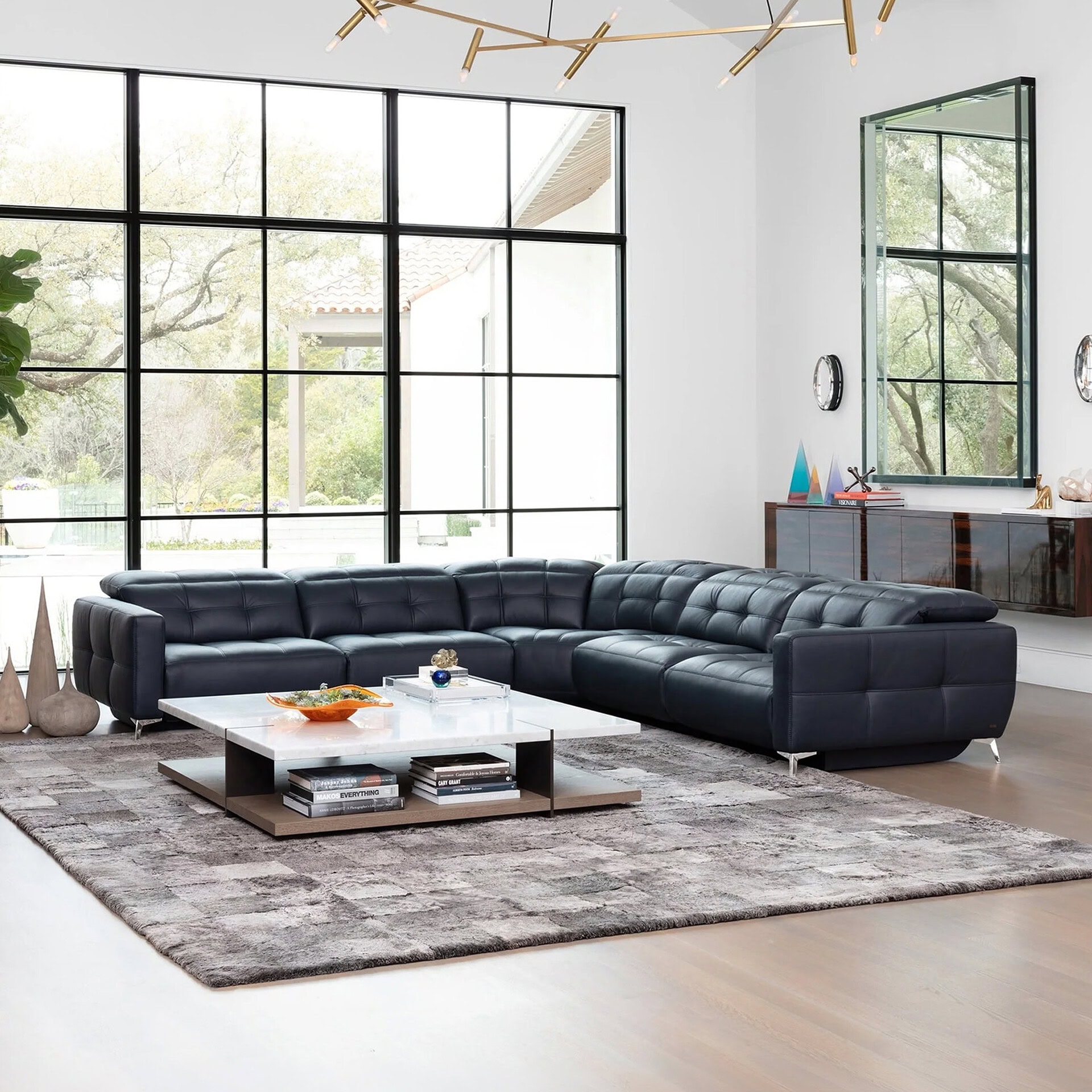 Verona Modular Motion Sectional Sofa in black leather, styled in a modern living room with large windows and contemporary décor.
