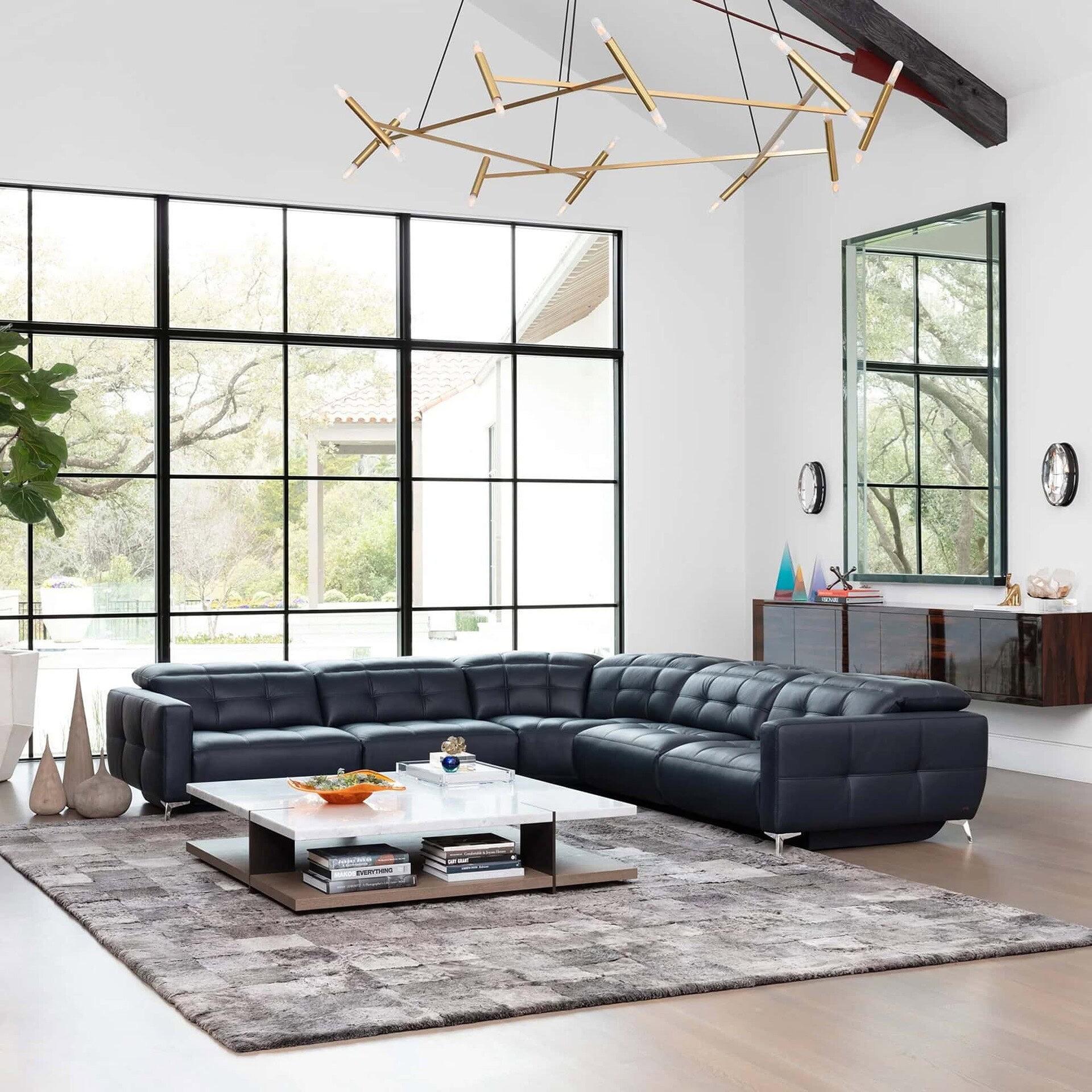 Verona Modular Motion Sectional Sofa in black leather, styled in a modern living room with large windows and contemporary décor.