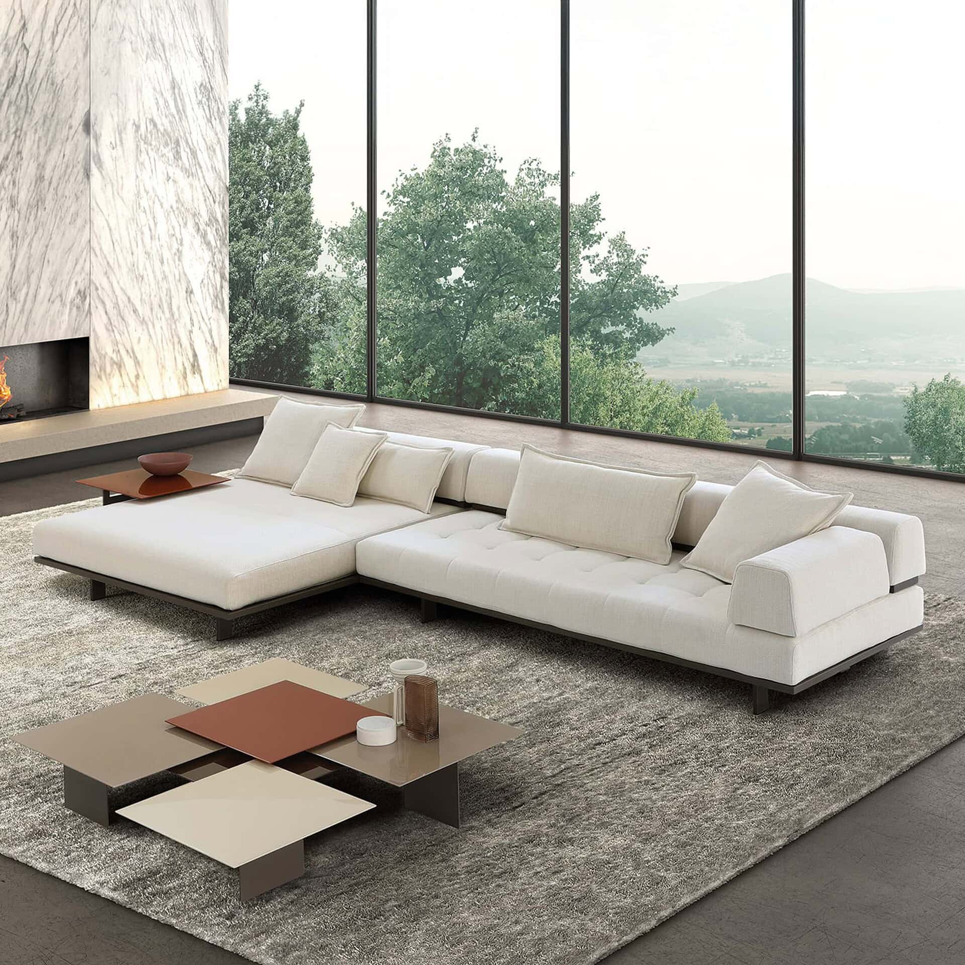 Luxurious modern white sectional sofa in a bright living room with large windows overlooking nature.
