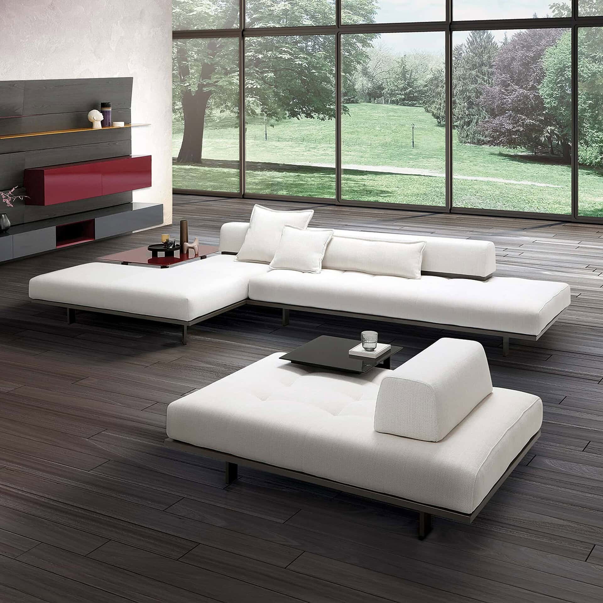 Modern white sectional sofa in a spacious living room with large windows overlooking a green landscape.