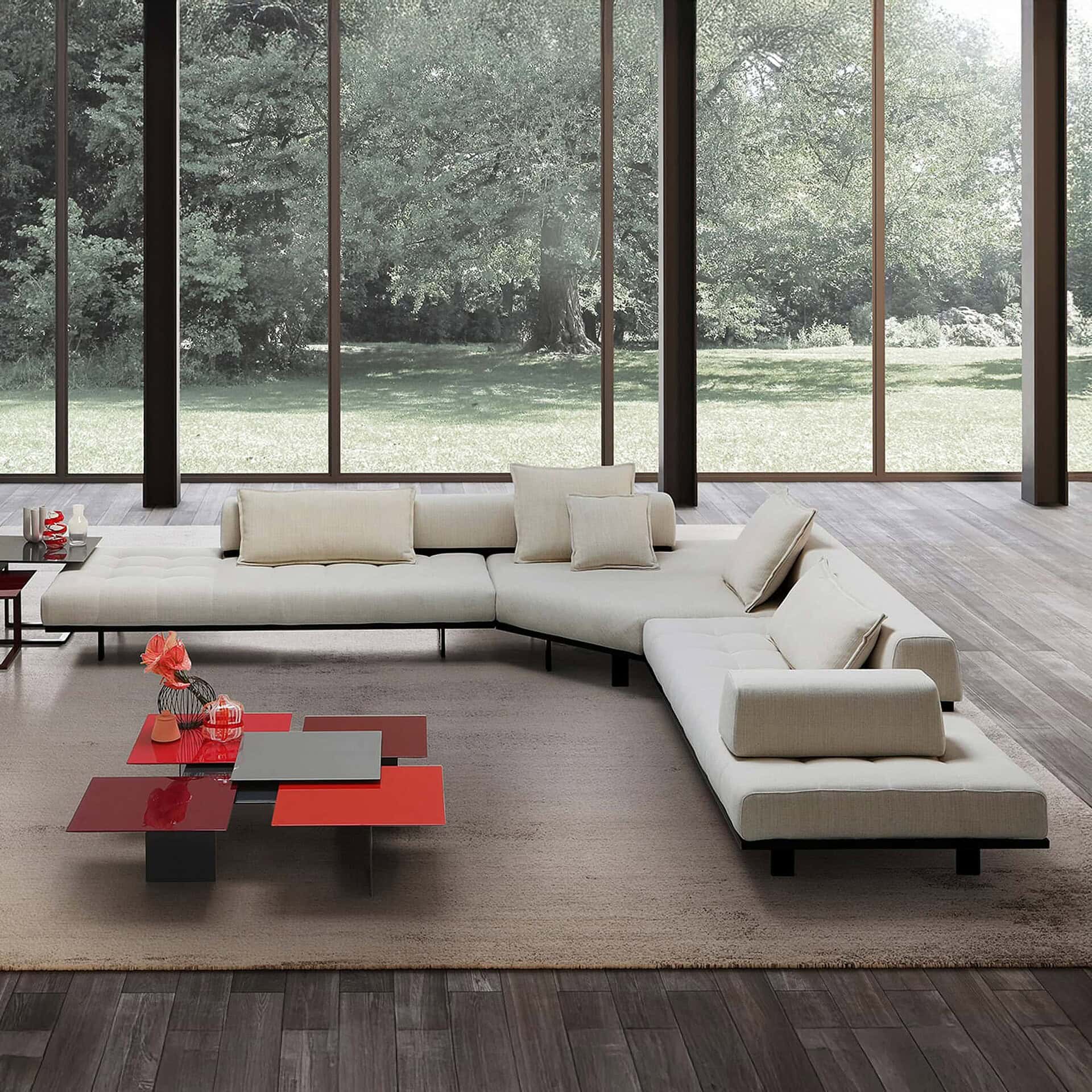 Minimalist cream sectional sofa with black legs in modern living room overlooking outdoors.